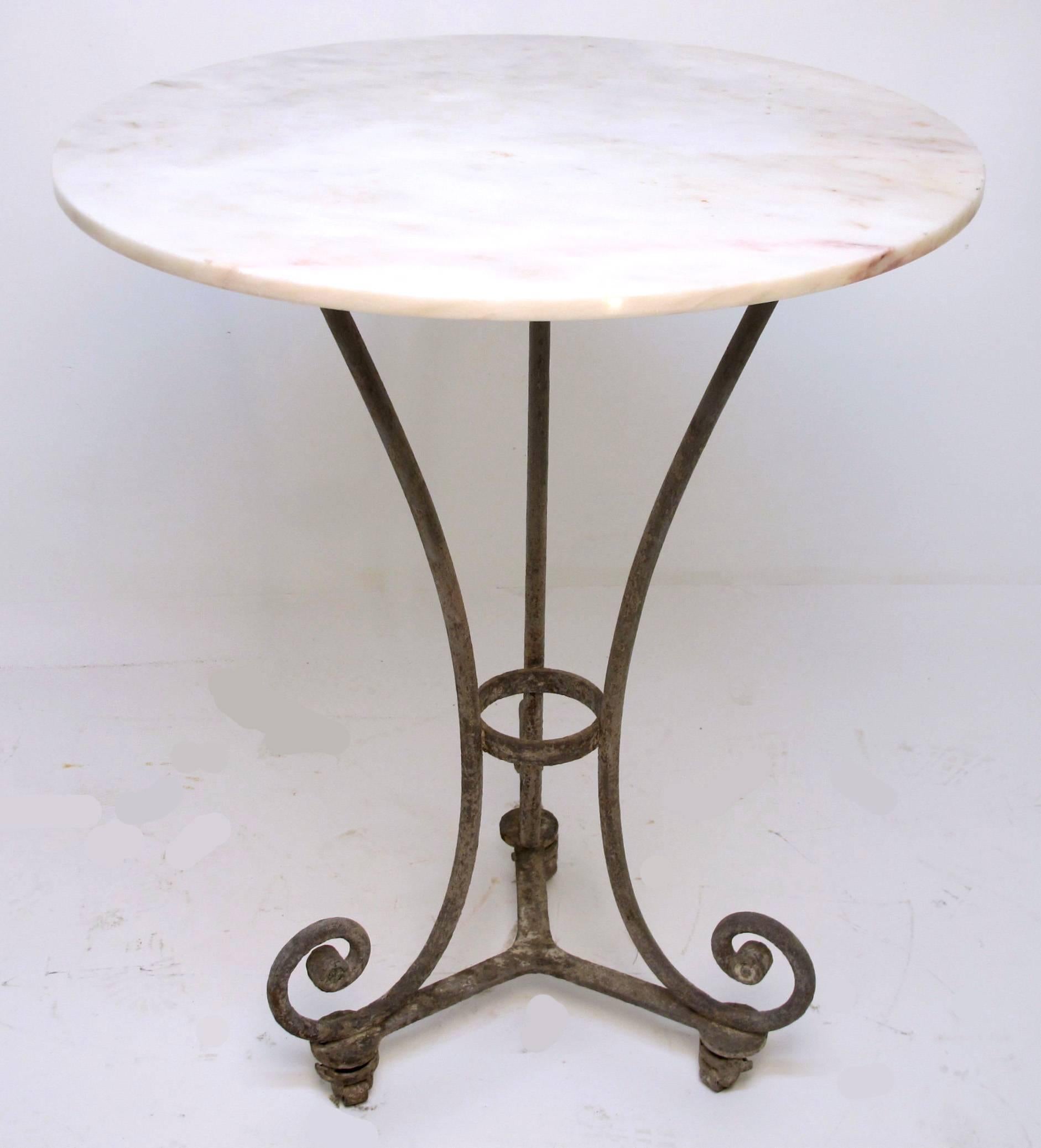 An unusually tall cafe table with marble top, having a beautifully weathered and patinated iron base. French, late 19th century.