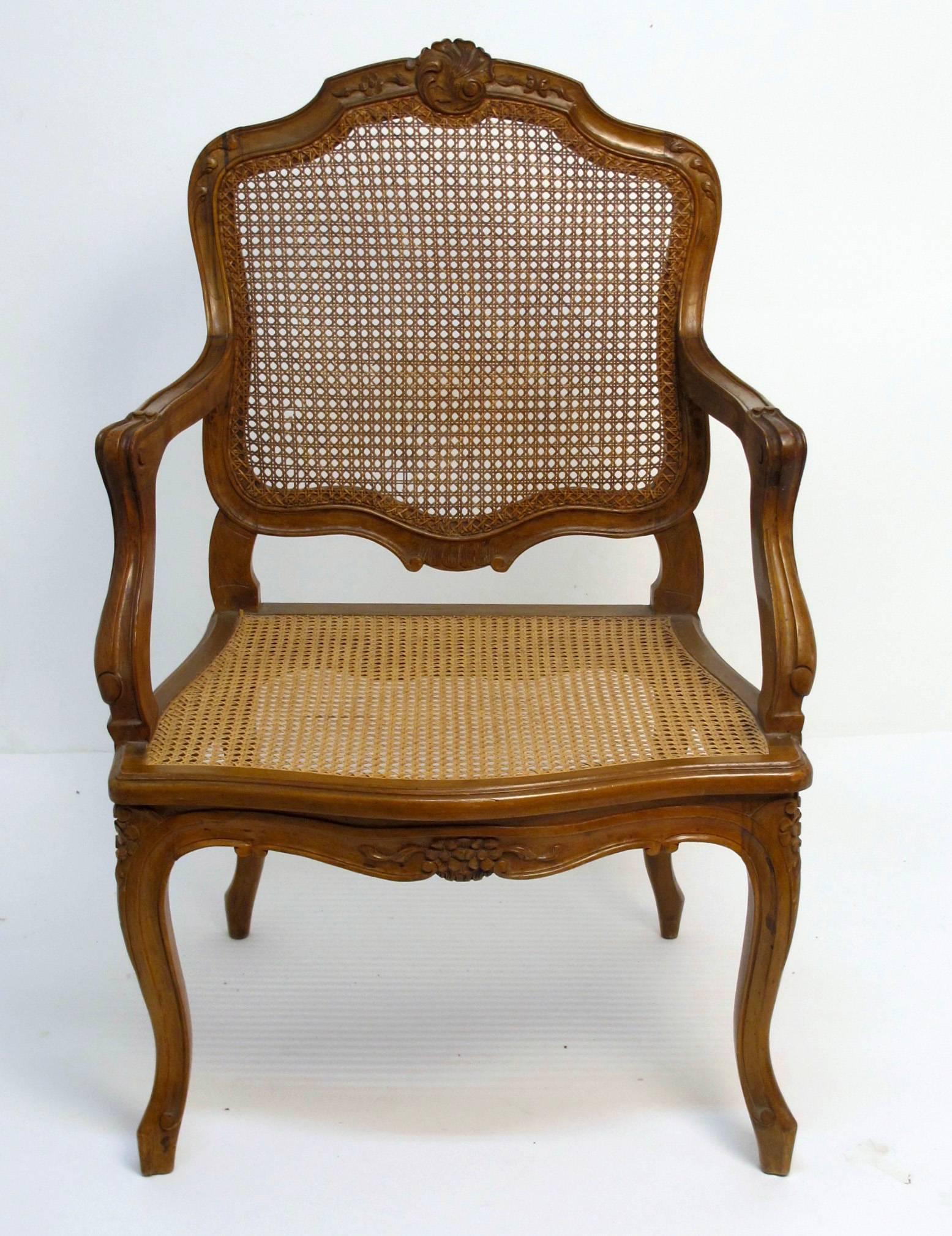 An 18th century Louis XV style armchair, elegantly carved beech wood with caned seat and back. France, early 20th century.