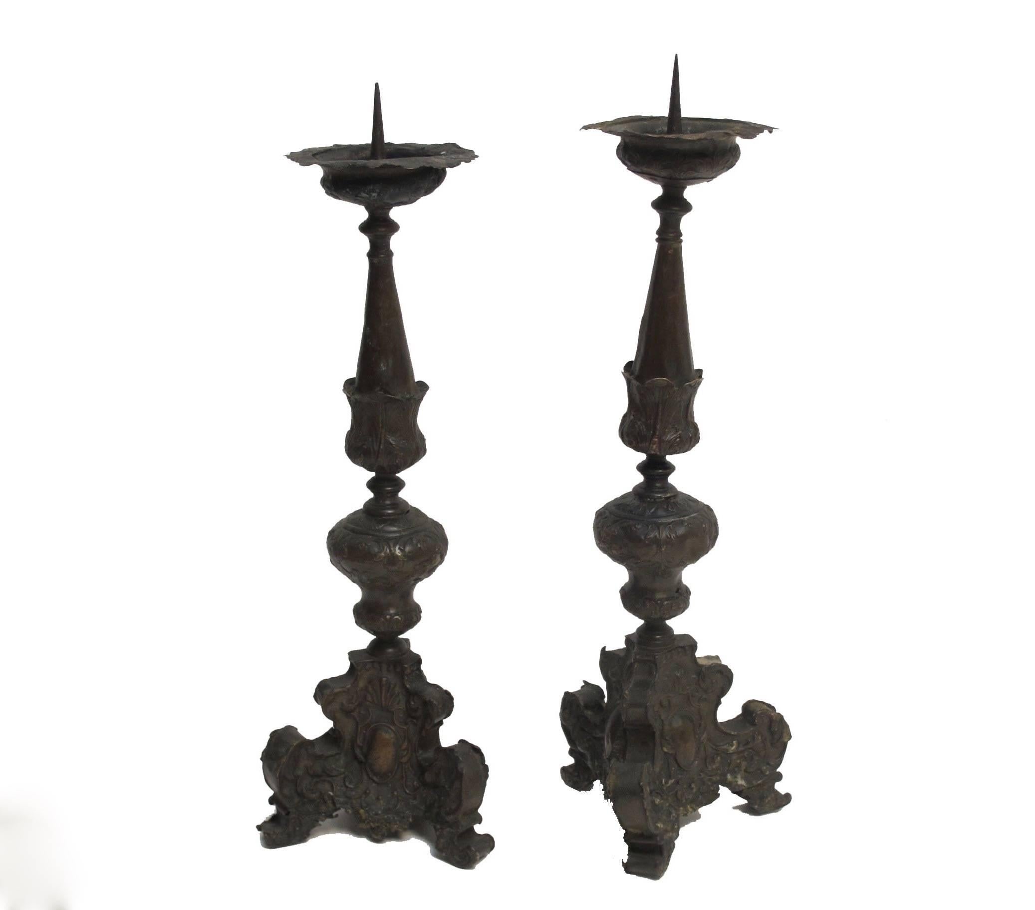 A pair of handmade copper pricket candle holders with fine embossed detailing of leaves, cartouches, sitting on scrolled feet, Italian, 17th century.