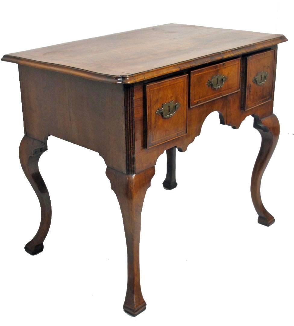 Walnut and burl walnut lowboy with crossbanding around the top, satinwood inlay on the front, and having original brass pulls. Standing on cabriole legs ending on Spanish feet, England, 18th century, circa 1760.