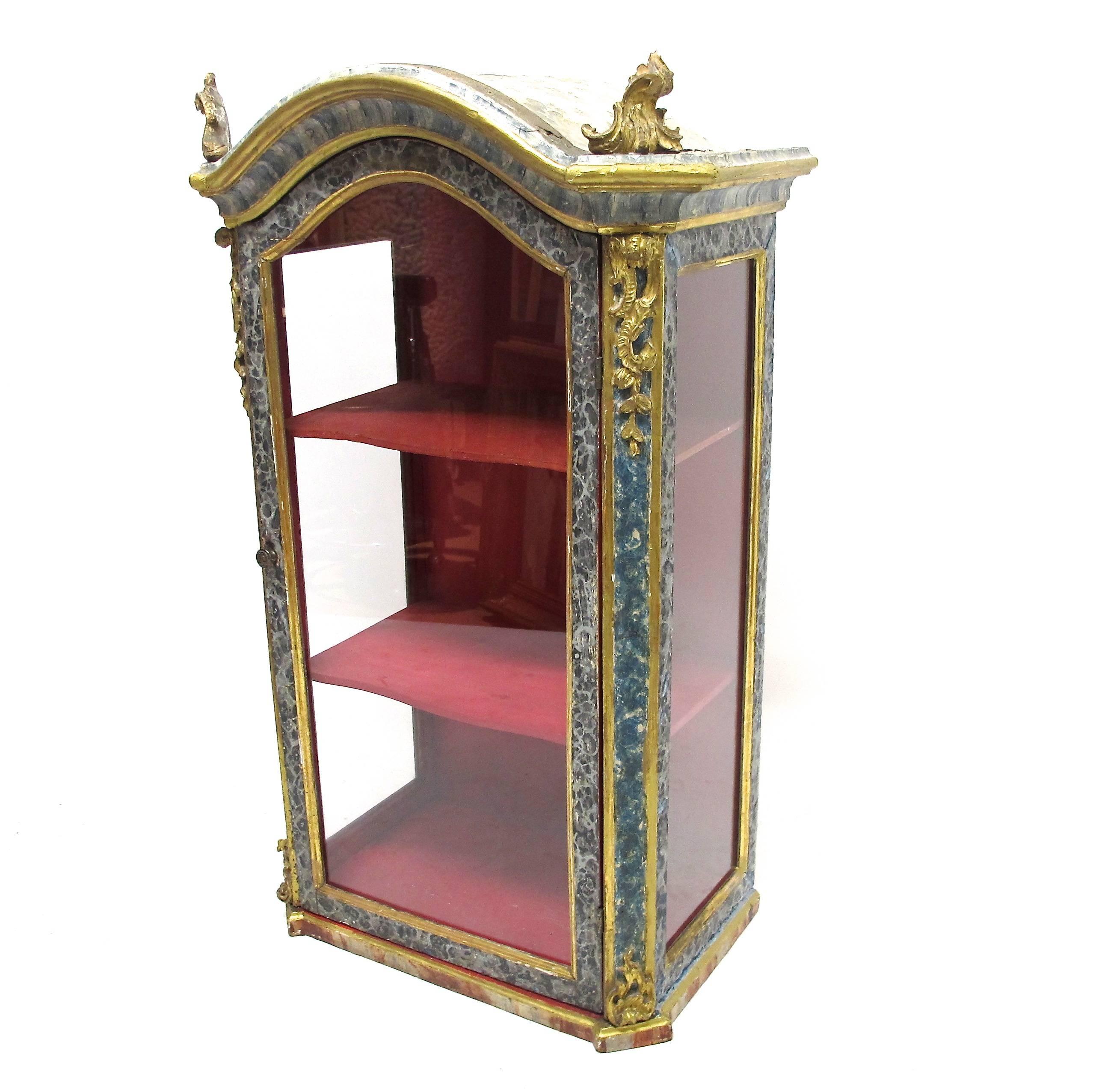 Original faux marble painted cabinet with gilt decoration and giltwood finials. Glass door and sides with two inner shelves. The interior red paint is new and the shelves were added sometime in the mid-20th century. In remarkably good condition,