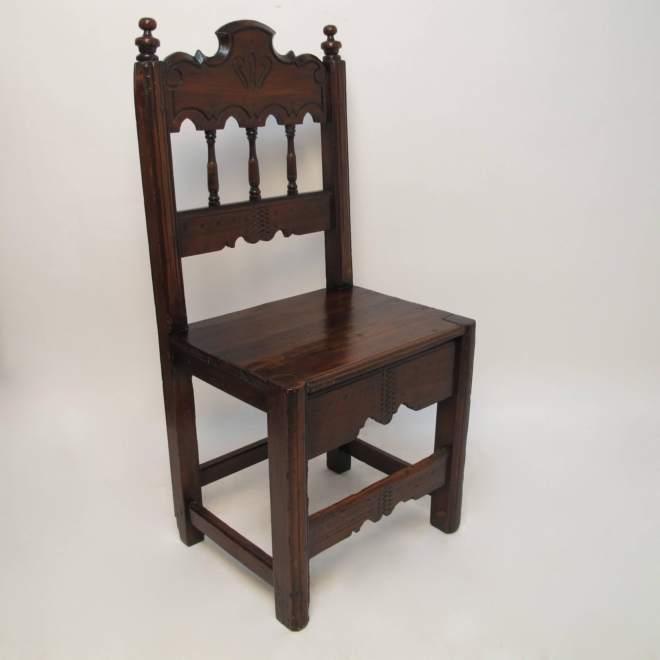 Unique set of four pine dining chairs.  These are two pairs of near identical dining chairs with carved top rails with spindles connecting lower rail.  The seats are plank with a carved apron.  Latin American, Circa 1820.