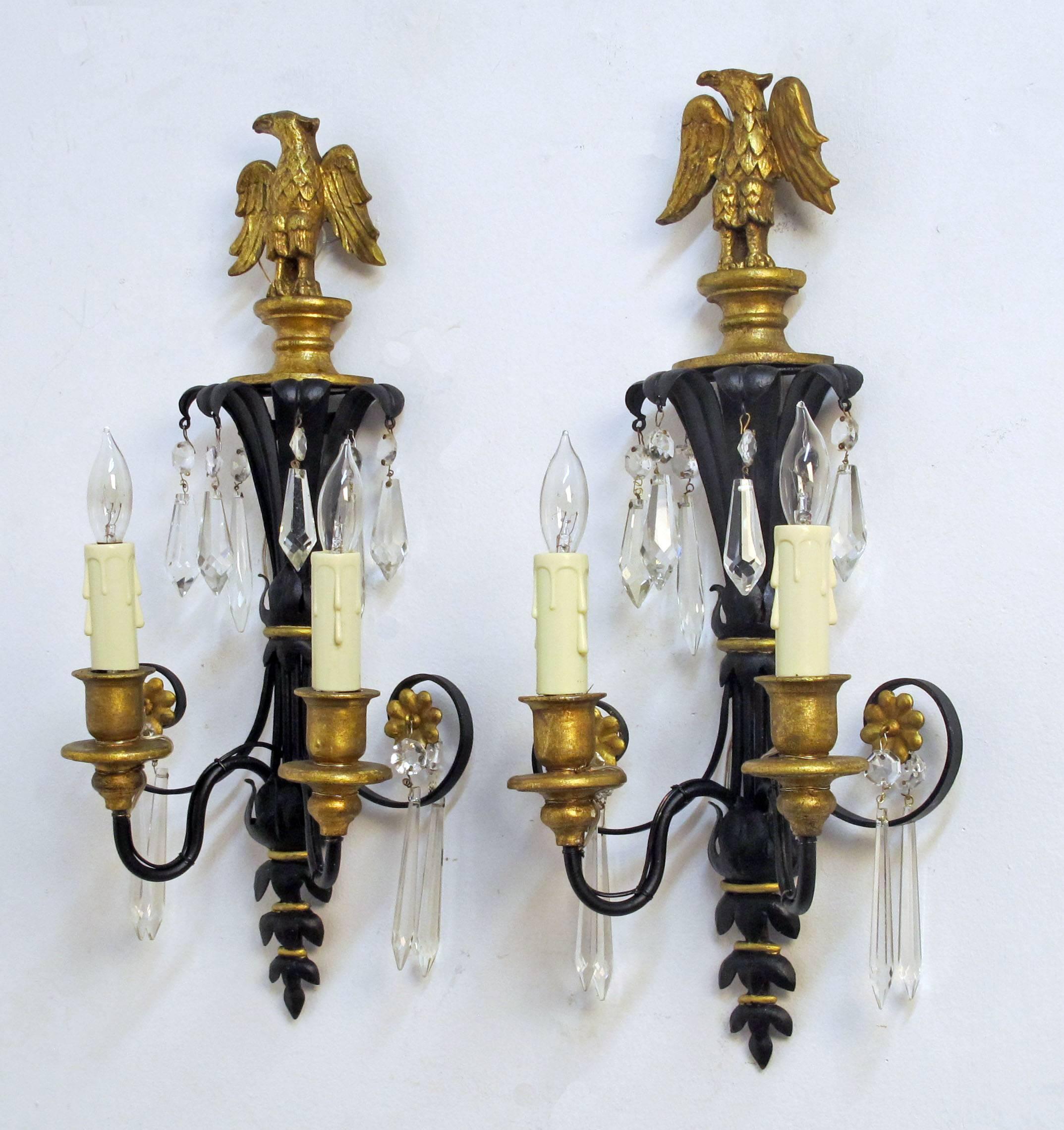 Pair of two light Black painted Tole and Gilt Carved wood eagle  sconces with crystal pendants and gilt accents.  Recently rewired  American, Early 20th Century.

