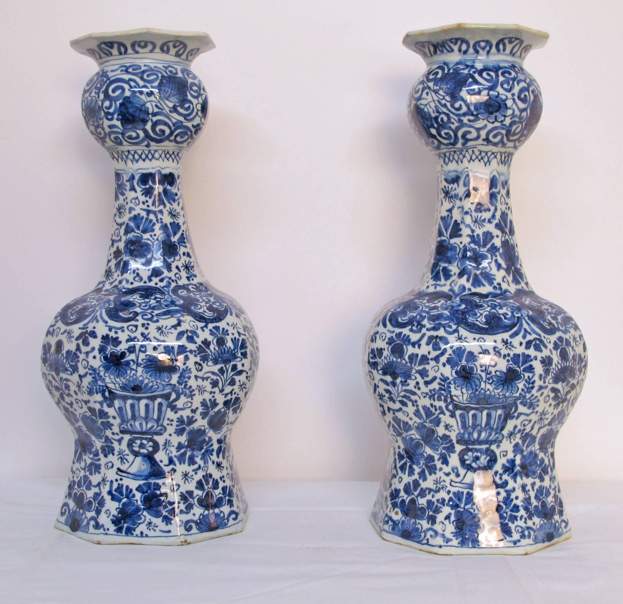 A pair of hexagonal shapedl blue and white tin glazed faience pottery vases with hand painted blue and white flowers and scrolling vines.  Holland, 18th. Century.  Some restoration to the rim of each vase.
