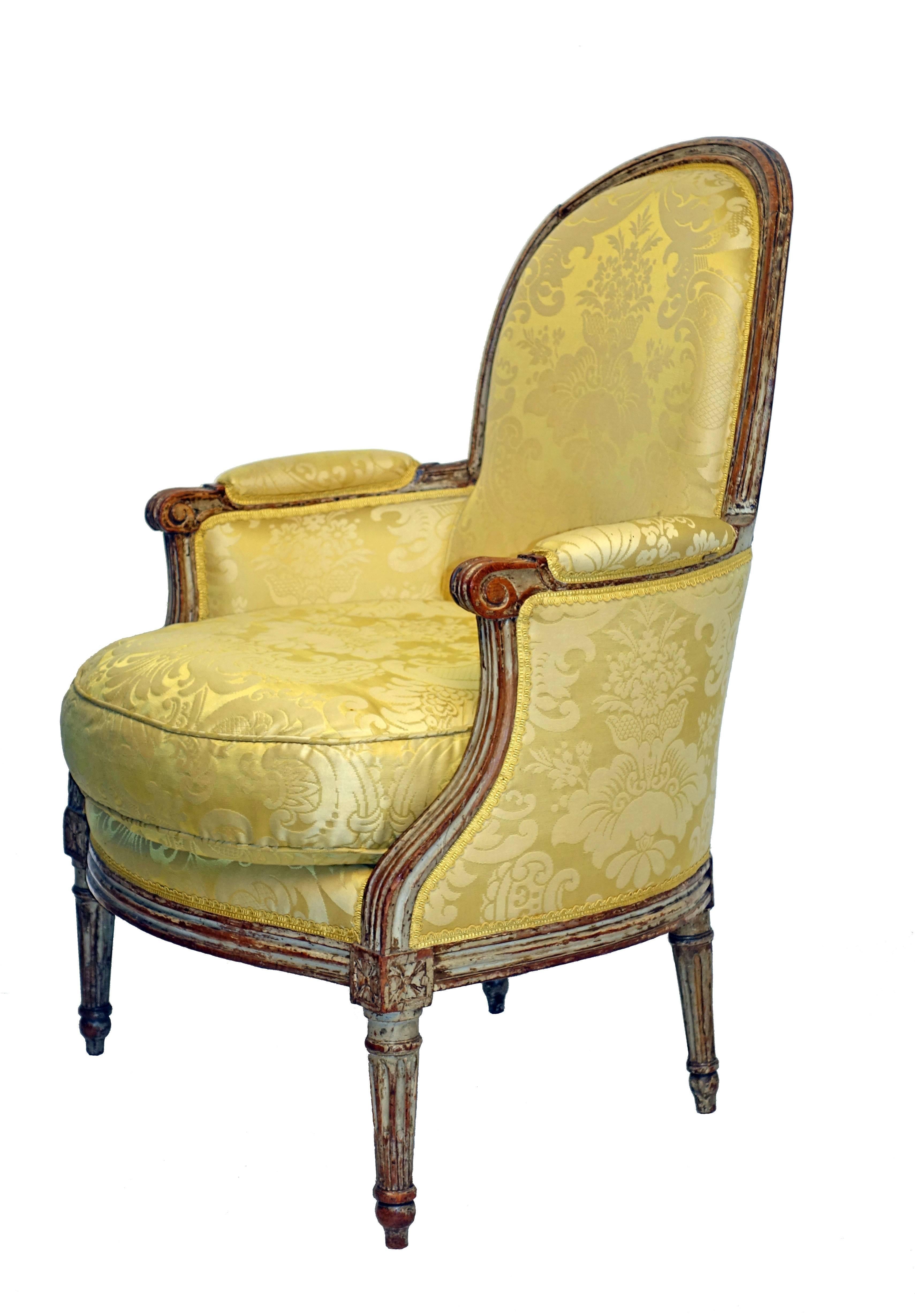 Carved and painted Louis XV style Bergere chair, having silk damask upholstery and a down cushion. Upholstery is in very good condition. France, late 19th-early 20th century.