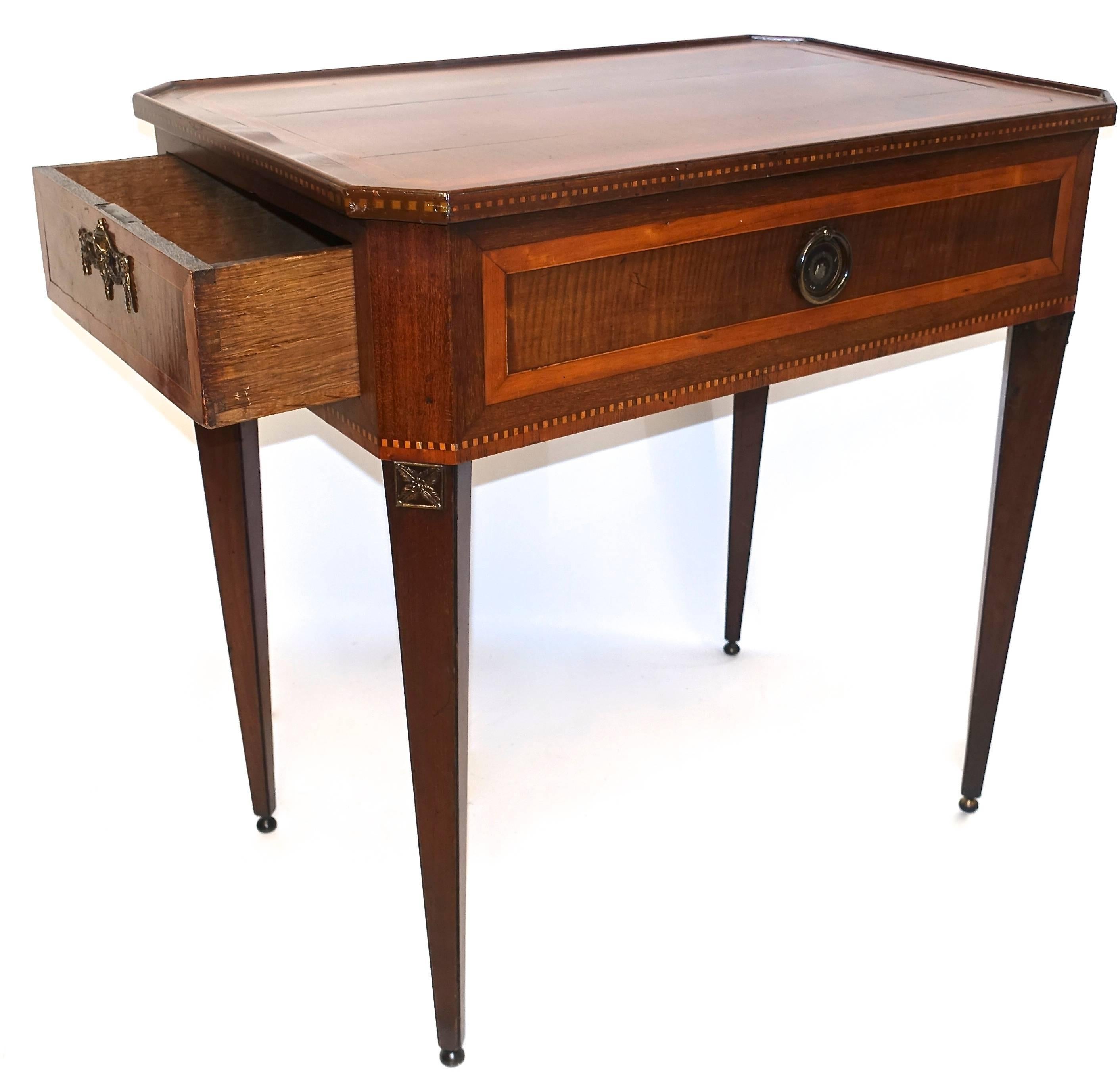 Neoclassical mahogany centre or tea table with single drawer at one end. Satinwood inlay on the top and as a dental detail around the top and base of the body. Decorative Brass pulls on either side and a decorative brass fillet at the top of each