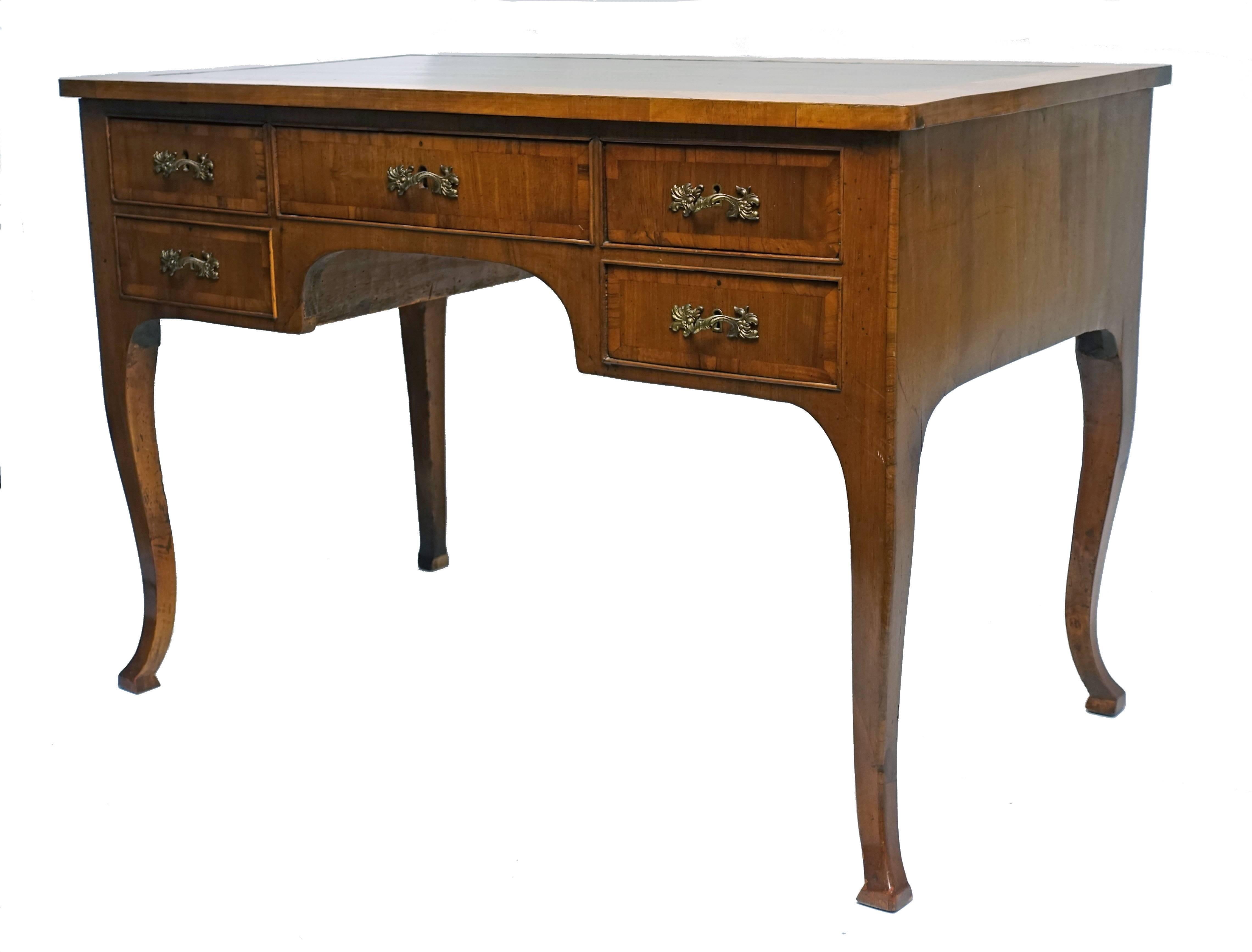 Neoclassical walnut desk with satinwood banding around the green leather writing surface and around each of the drawers, standing on cabriole legs with square foot pads. Italy, mid-19th century, circa 1860.
