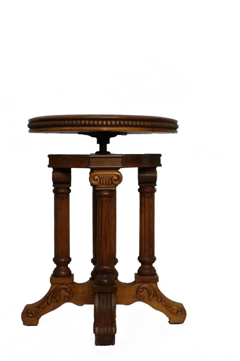 An exceptional oak and maple piano stool. Four Corinthian fluted columns supporting a round adjustable seat with carved beading, and sitting on scrolled feet. Seat adjusts up to 29 inches high. America, circa 1880.