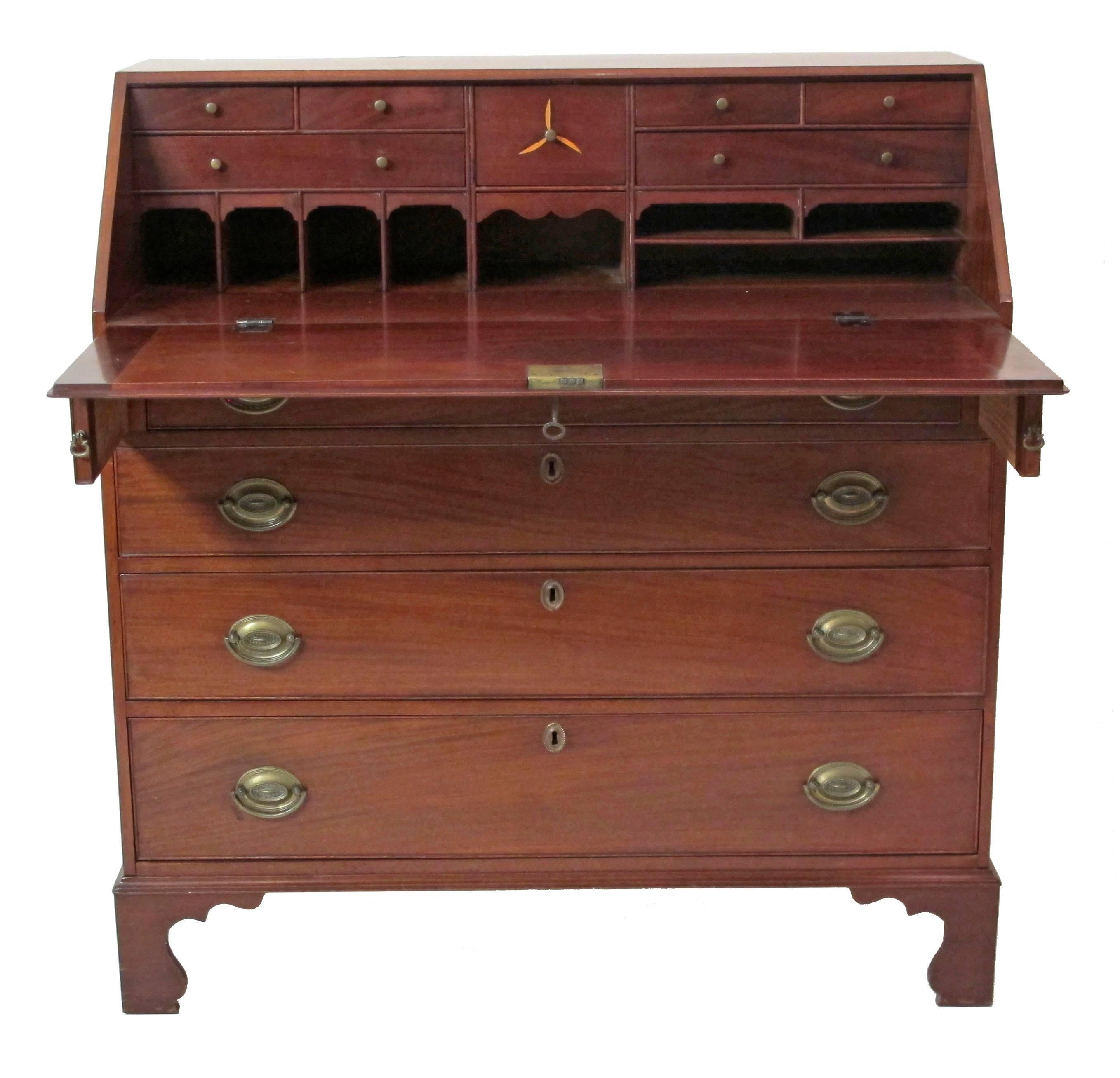 Georgian Mahogany fall front desk with fitted interior of nine small drawers and seven pigeon holes, the top supported on two slide out supports above four graduated drawers and brass pulls, standing on shaped bracket feet.  English, Circa 1800.
