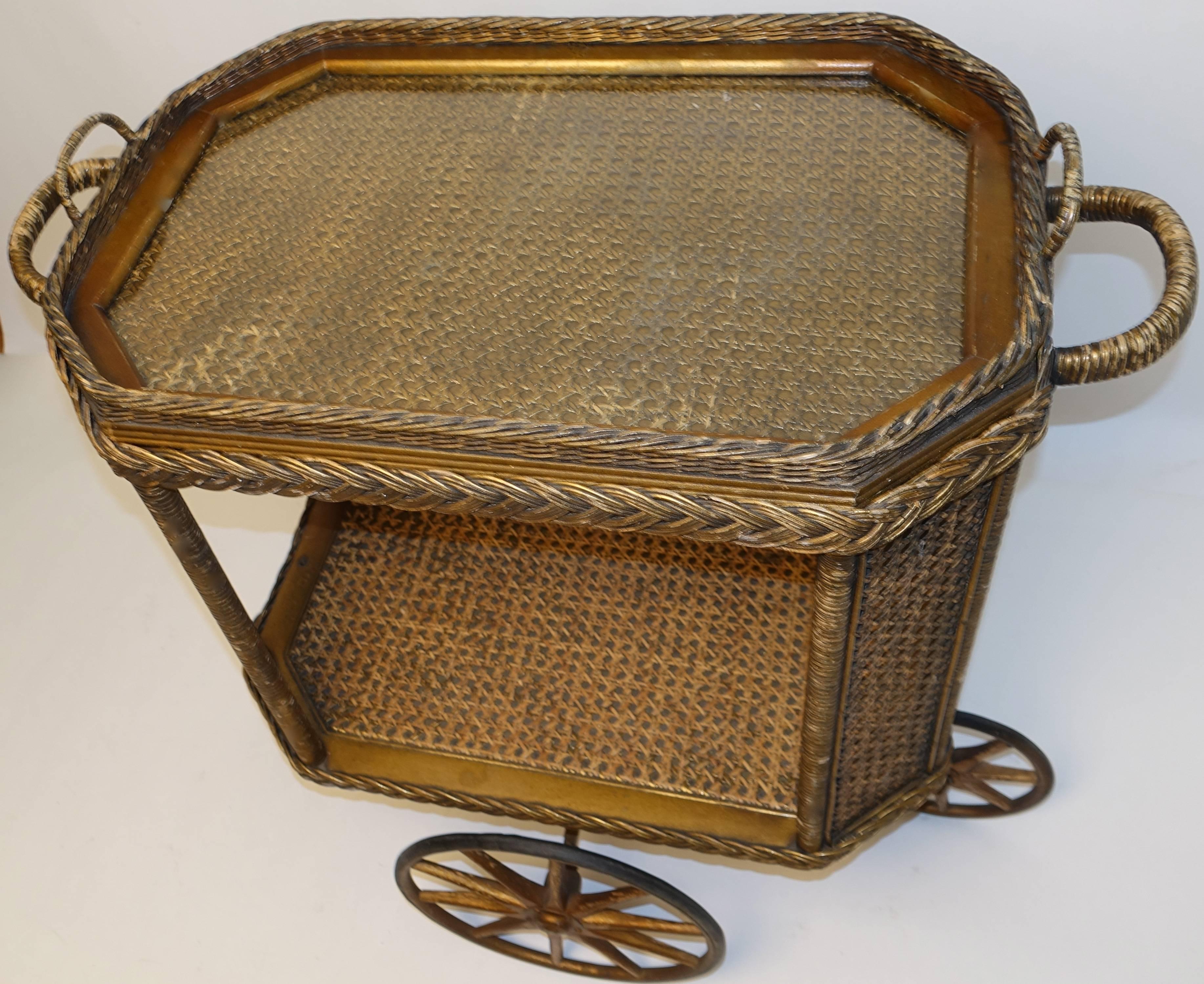 Original Heywood Bros. Wakefield Co. wicker and cane bar cart drinks cart with removable tray. The gold finish is original to the piece, all wheels are in working order the front and rear wheels allow the cart to turn in a 360 degrees.
Paper label