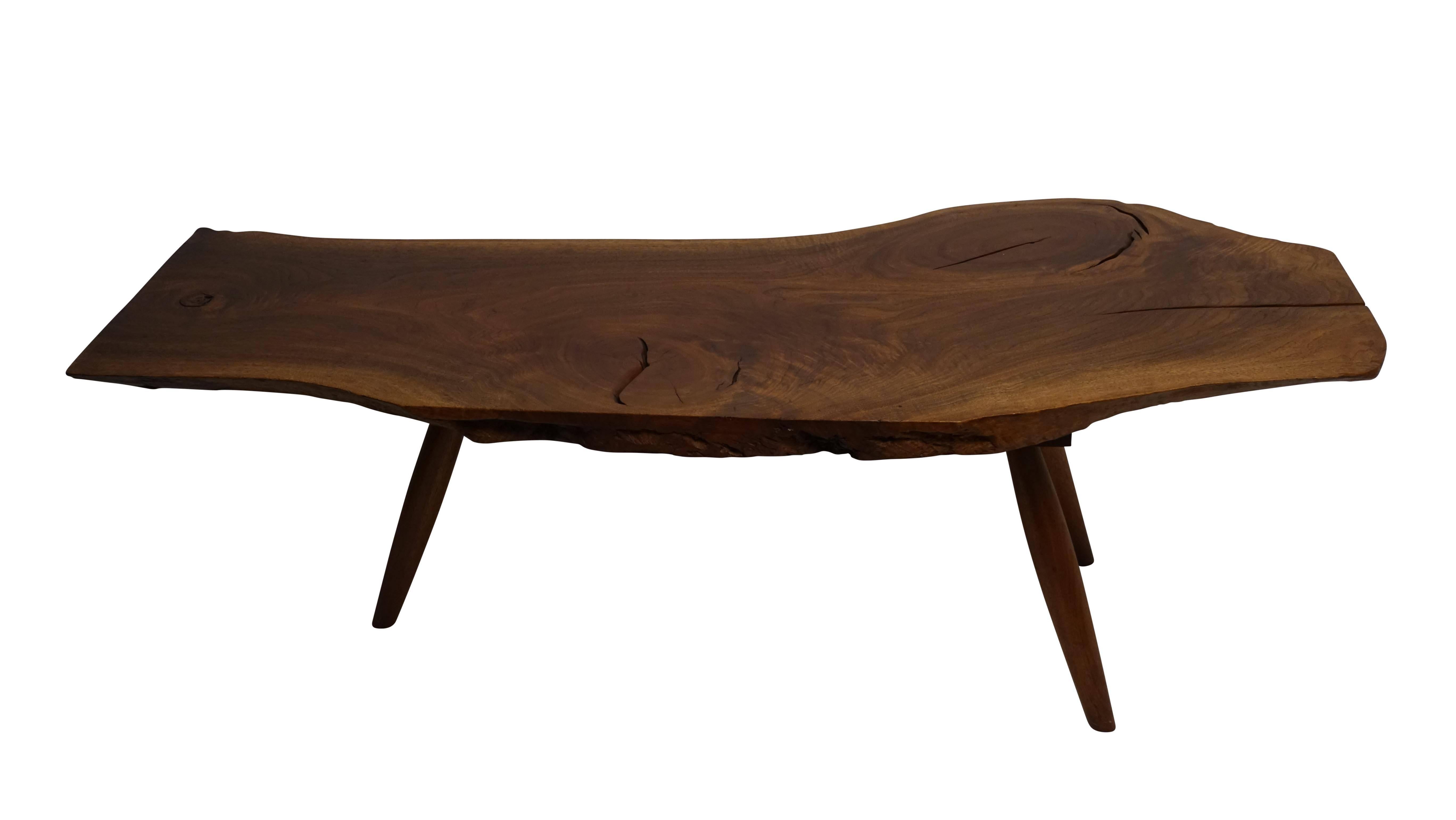 Beautifully figured walnut plank coffee table with three knots standing on tapering legs. American, circa 1970.