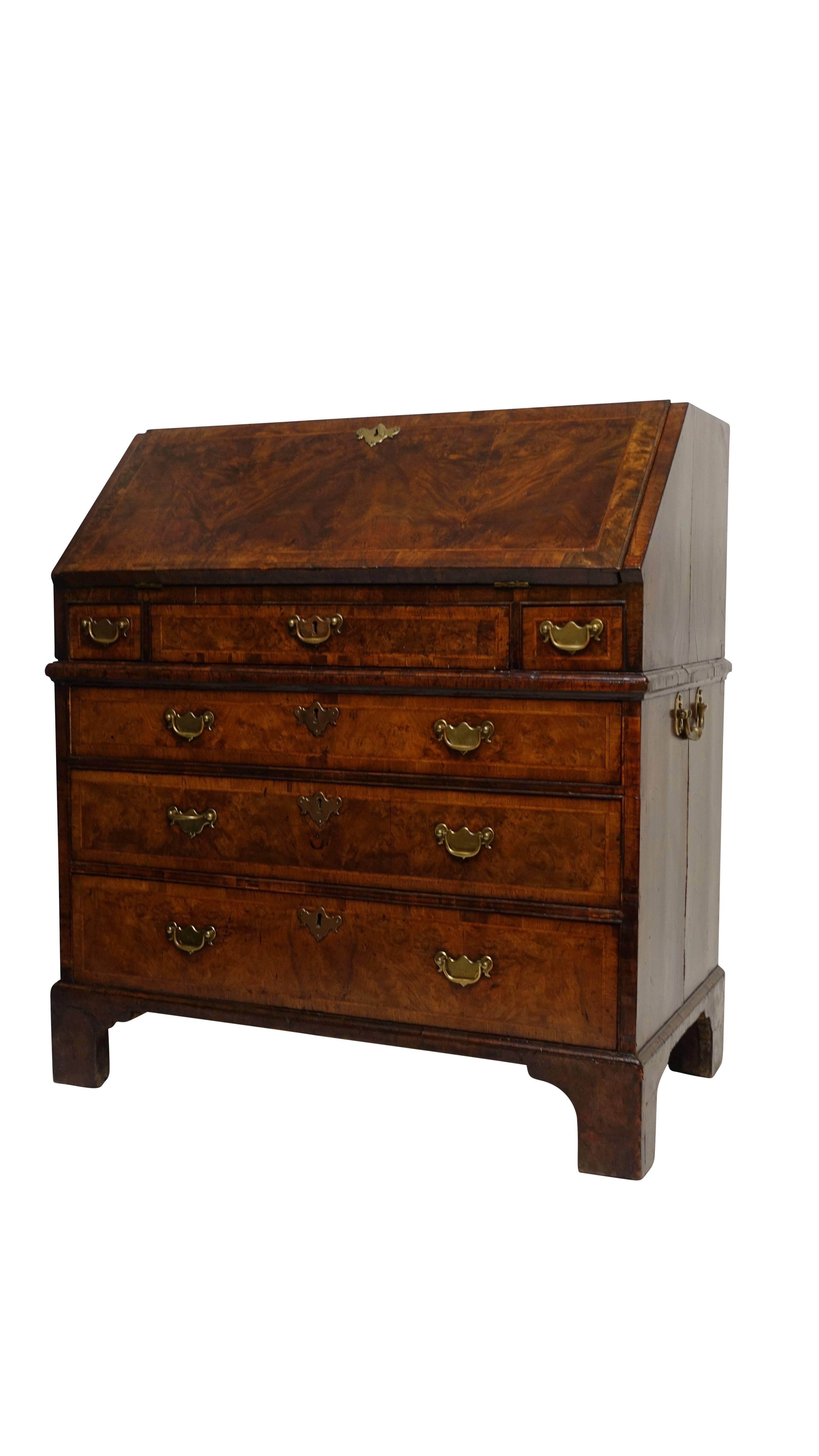 Beautifully made two-piece Georgian walnut with burl walnut slant front desk. Three short drawers above three graduated drawers having satinwood inlay with herring bone pattern, replaced brass drawer pulls and sitting on bracket feet. Interior