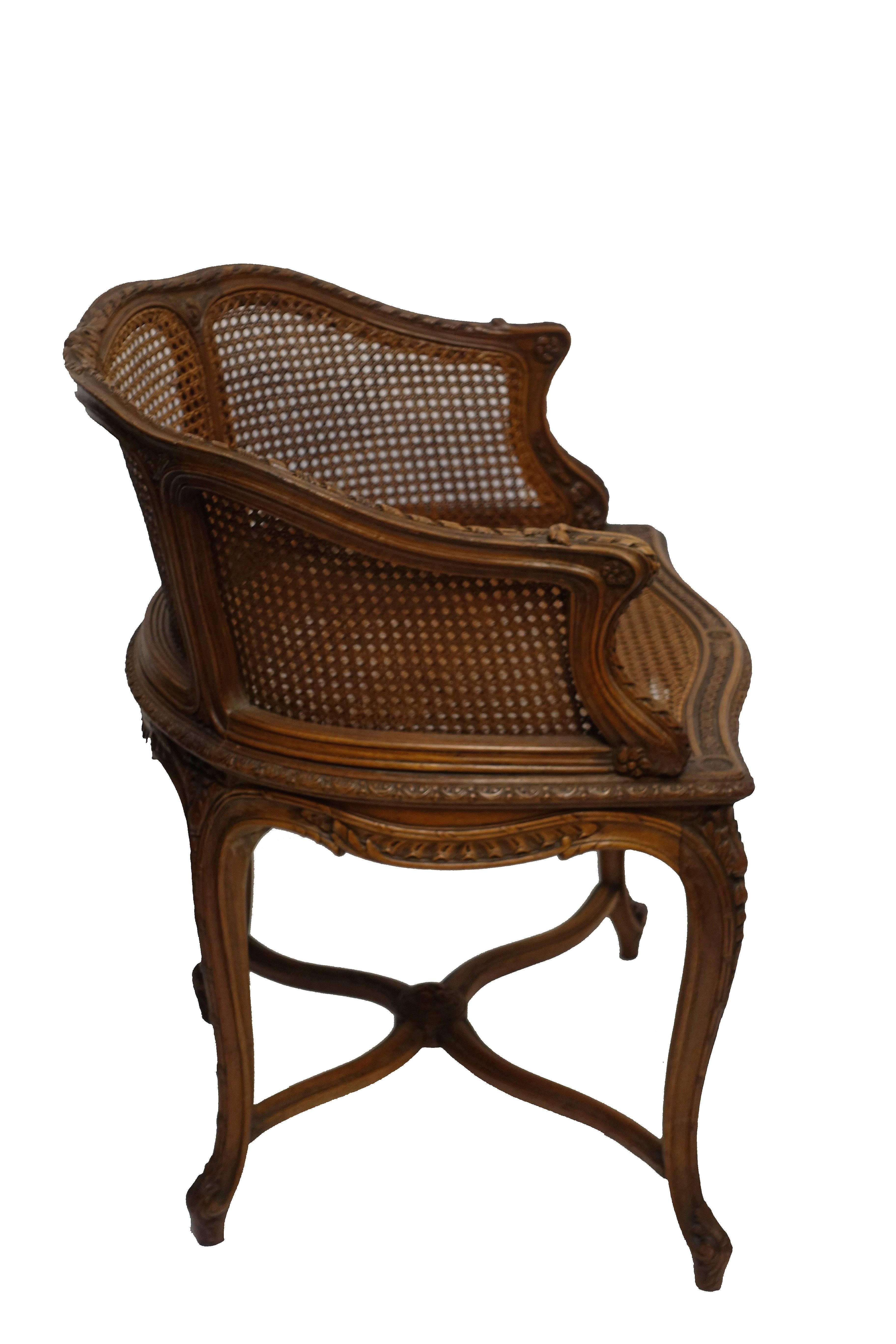 Highly carved walnut Louis XVI style vanity Bergere chair with caned seat and sides, France, circa 1900.