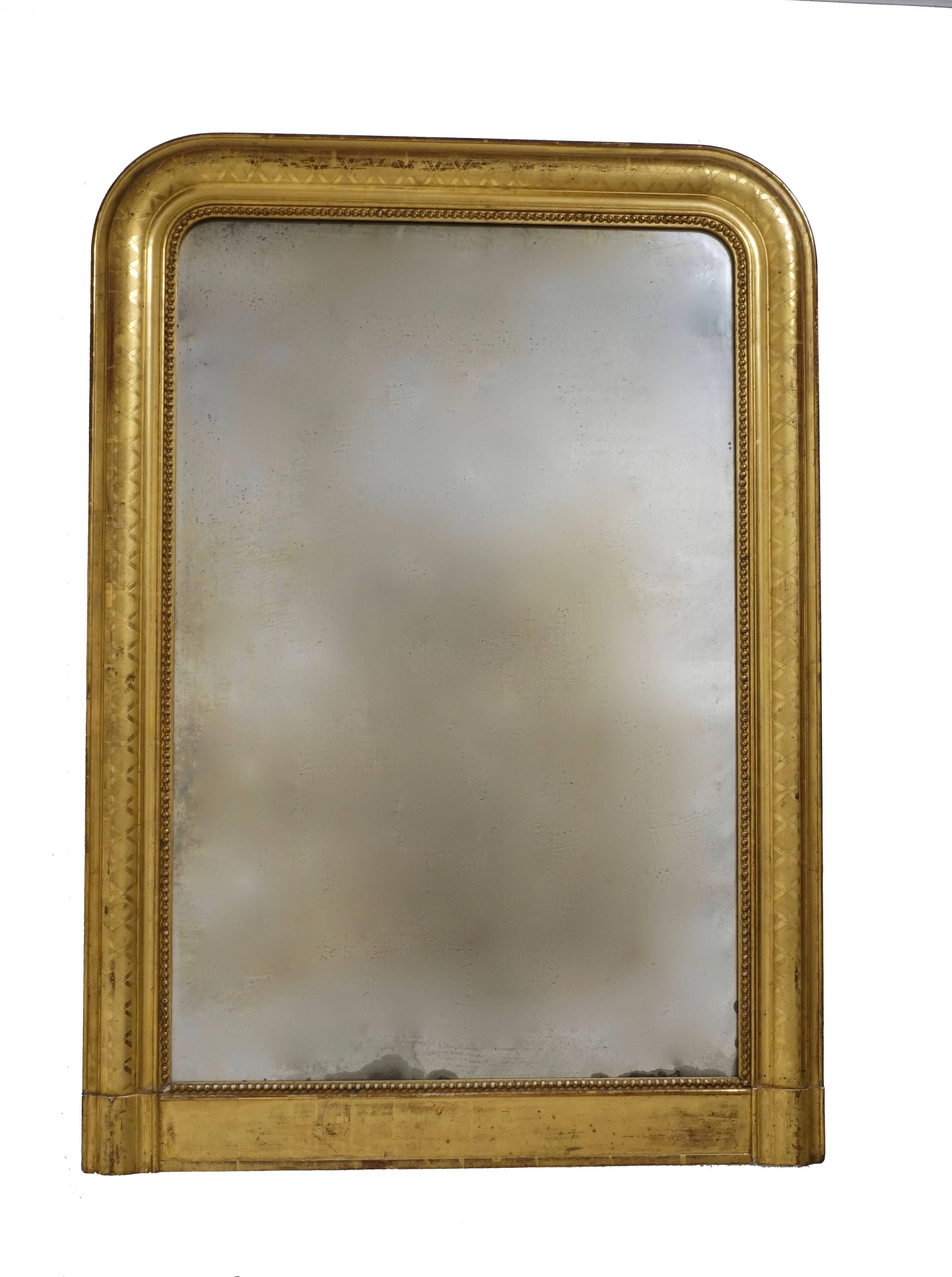 A Louis Philippe period beautifully gilt framed mantel mirror with etched X design on the bull nose molding and an inner band of dots around the original aged mirror plate, France, circa 1840.