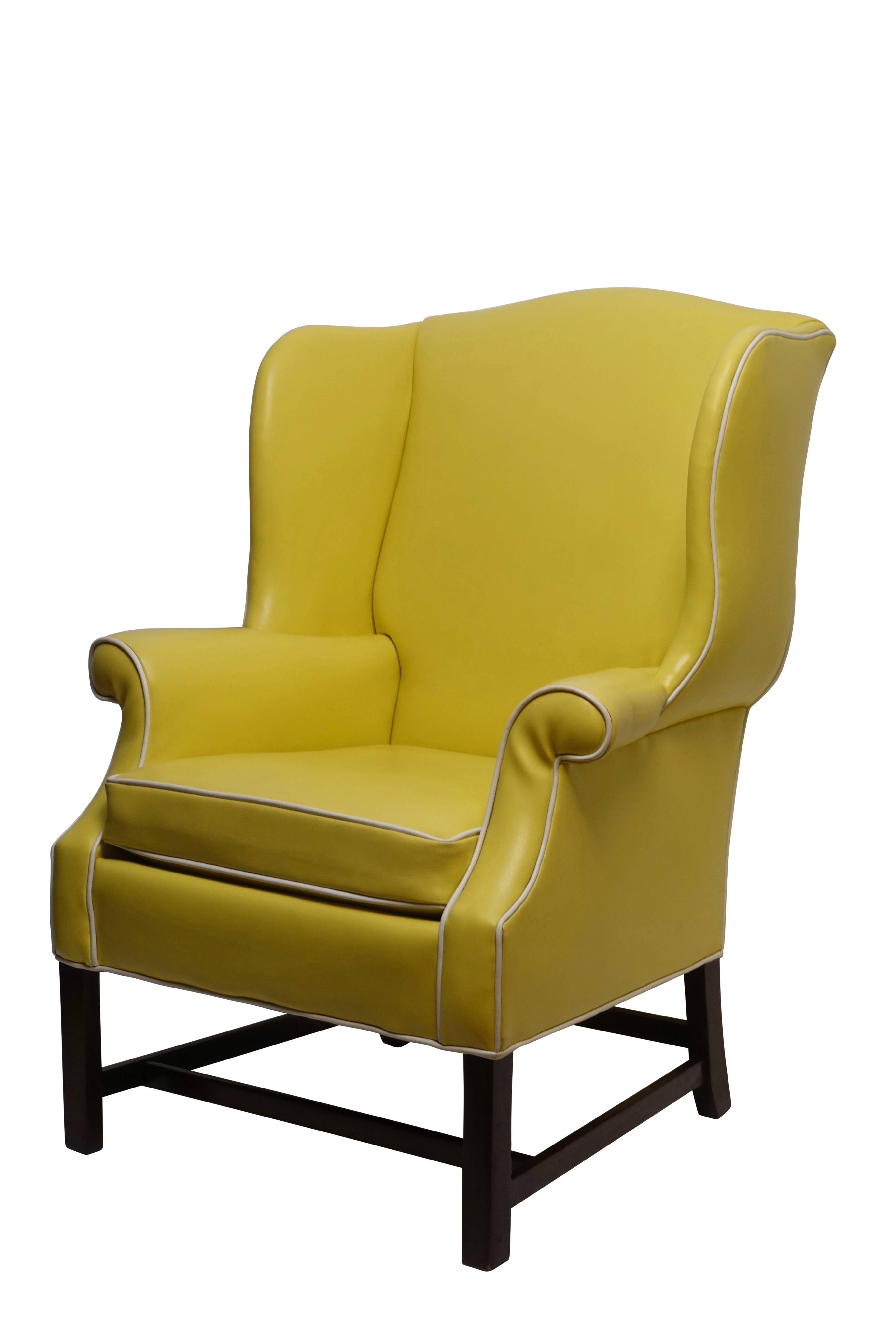 A pair of Georgian style yellow and white vinyl upholstered wingback chairs with white piping detail, mahogany legs and stretchers. Manufactured by Breuners for a design client, circa 1960s. Measures: Height-42