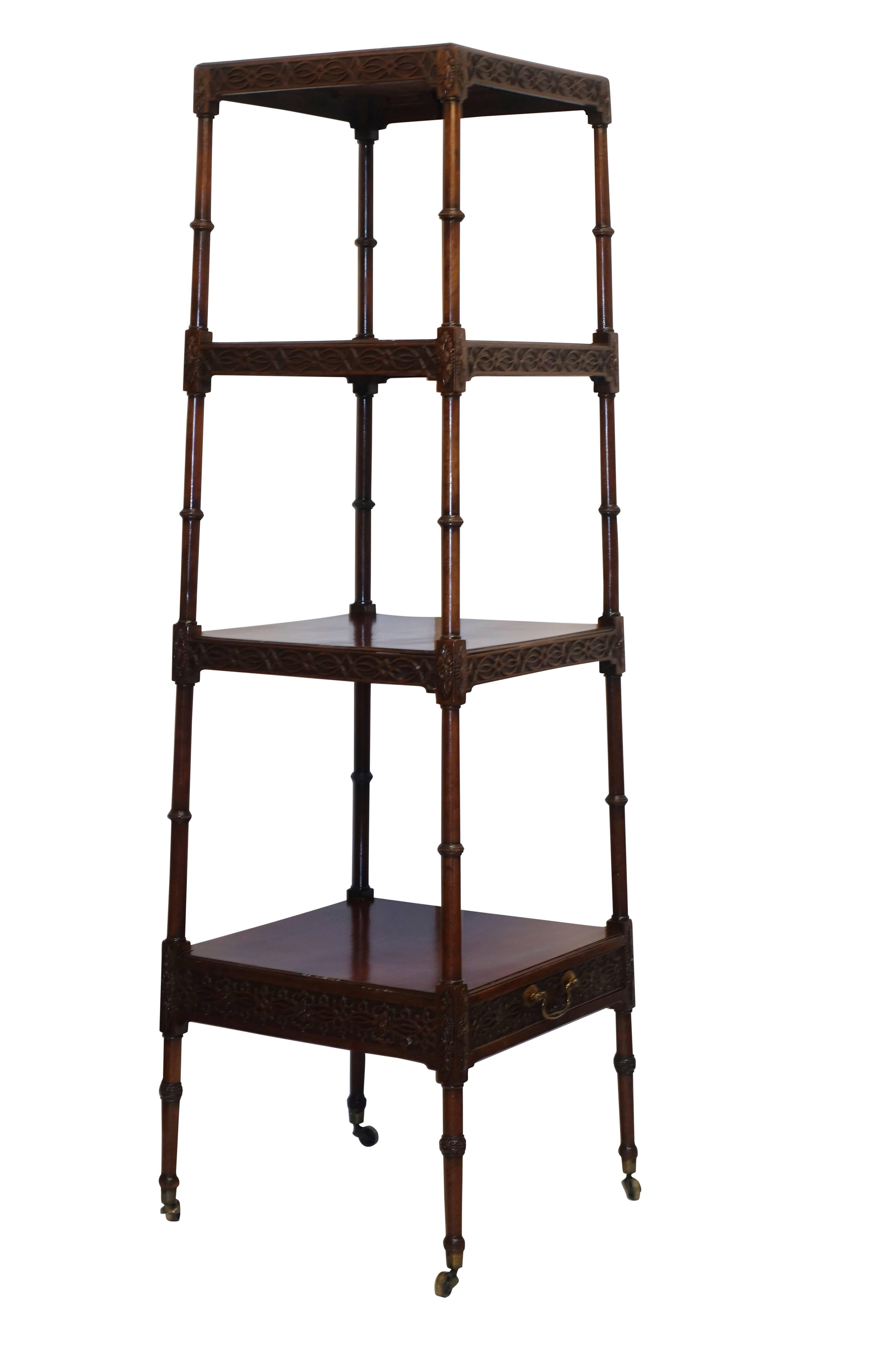 Unusual etagere with carved apron on the shelves and tapering turned supports from top to bottom, standing on the original brass casters, and having a single drawer under the lower shelf. England, circa 1830.