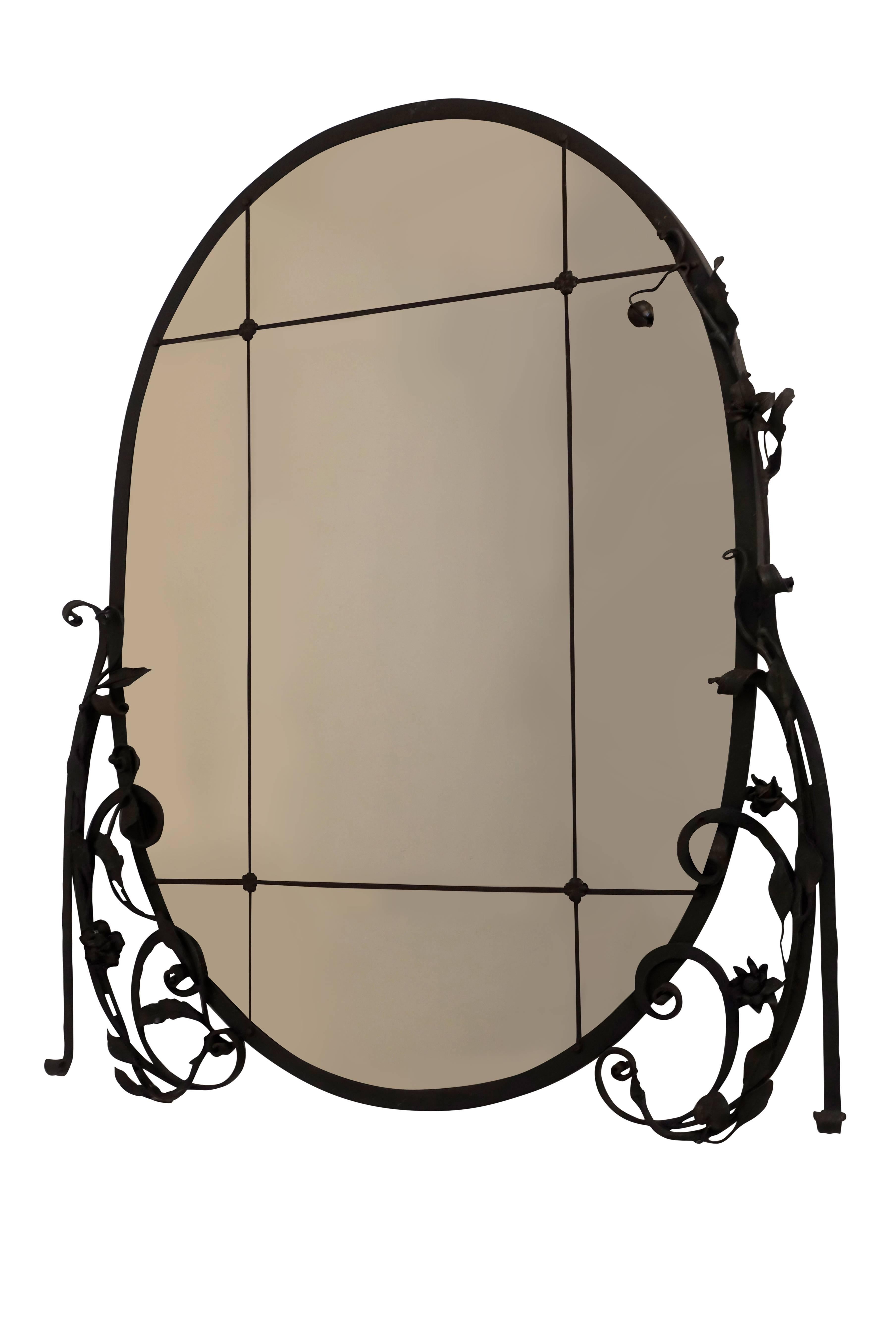 Oval shaped  glass mirror with wrought iron flowers and scrolling detail, France, 1920s.