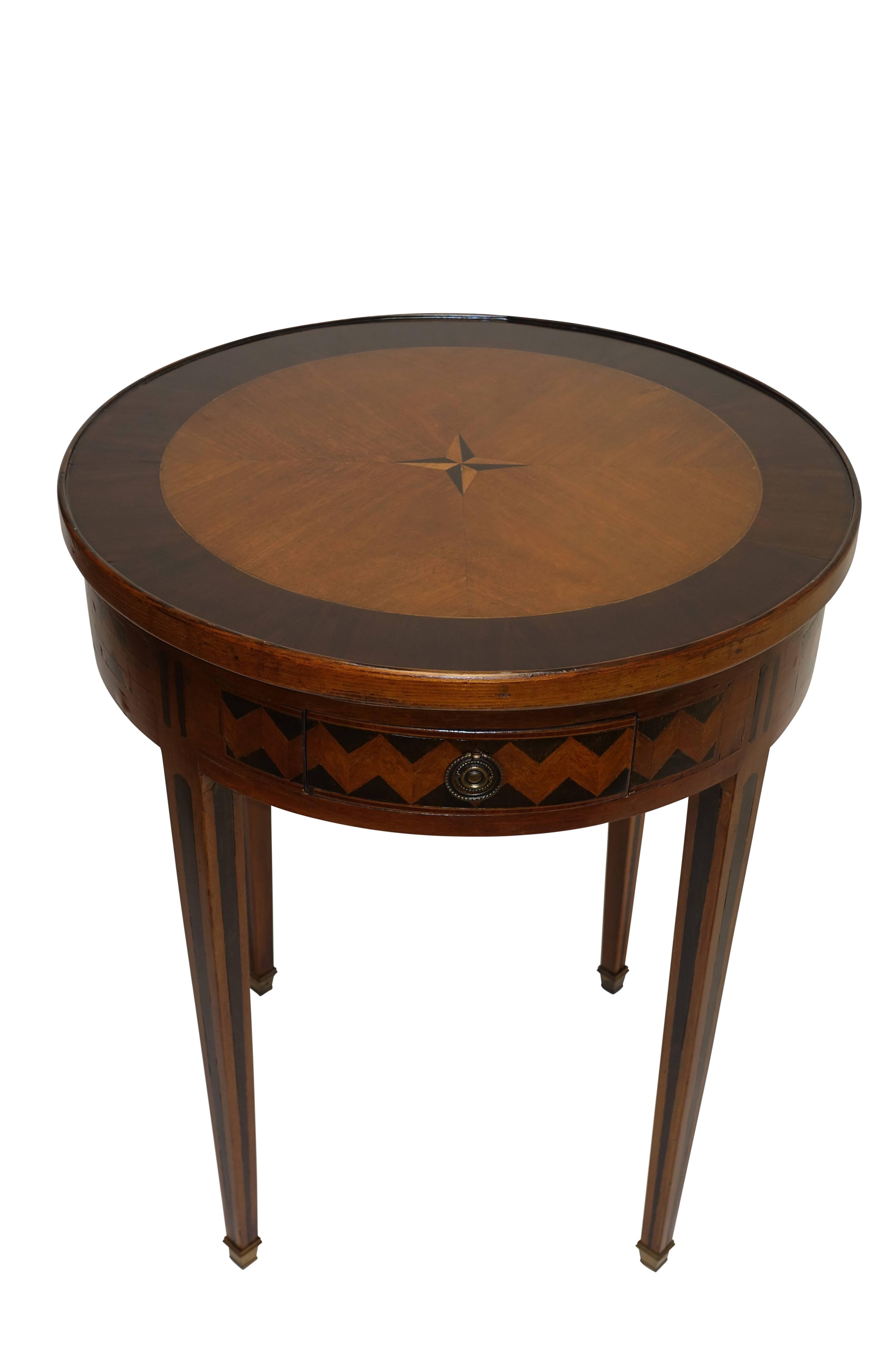 Circular game table inlaid with star design on one side, the reverse side inlaid with a chess board, underneath the two previous tops is a sueded card game surface. Having two short drawers and a pair of candle slides with inset leather tops. The
