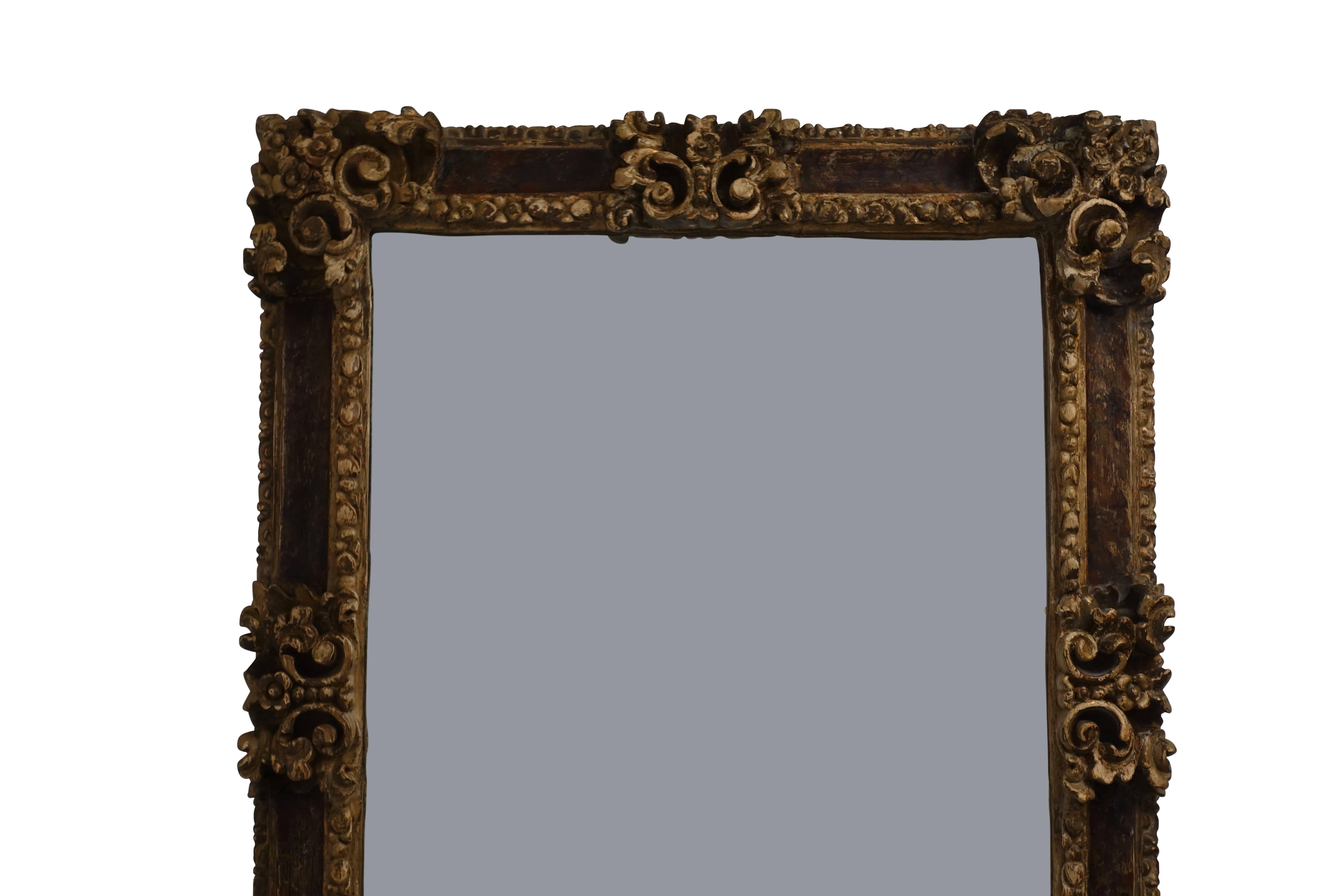 An early 19th century Spanish colonial carved, parcel-gilt and faux painted frame with newer mirror plate.
