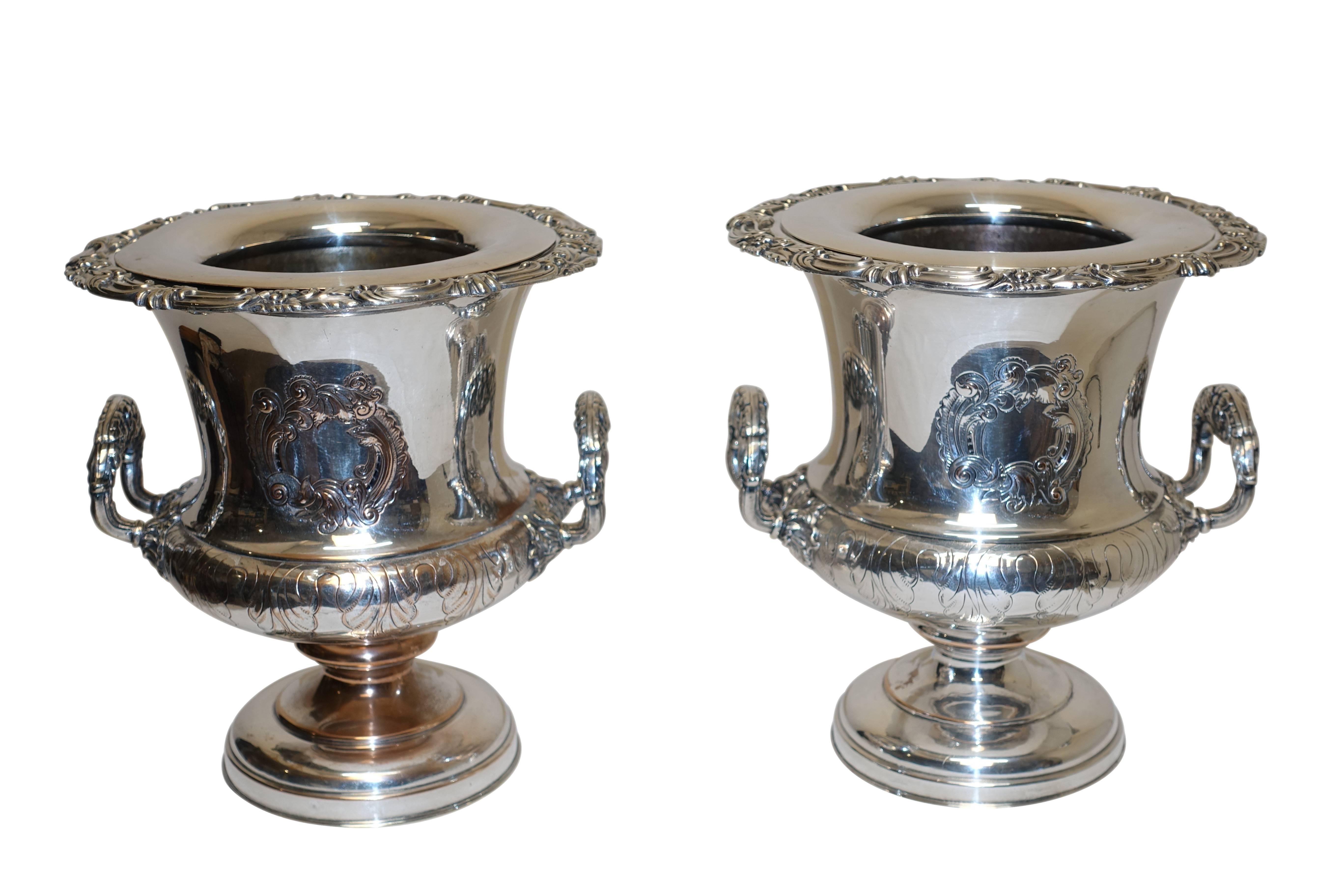 A handsome pair of Sheffield wine coolers with their original insert liners and rims. Having C scroll cartouches and elaborate floral handles. There are some areas where the copper is showing through the original Sheffield silver plate. England,