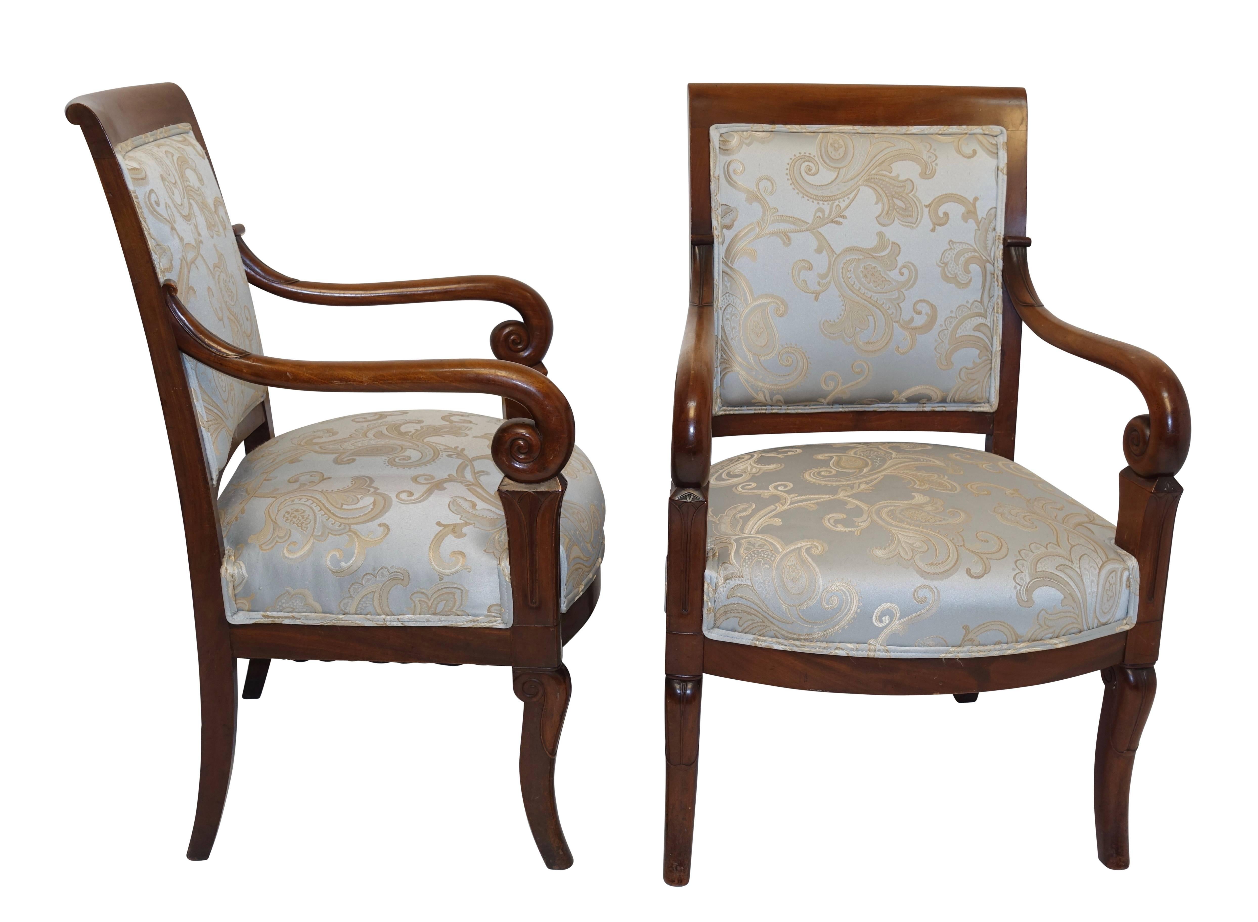 A pair of Charles X walnut fauteuils armchairs with sweeping and curled arms and saber style front legs. Upholstery in as found condition.
France, circa 1830.