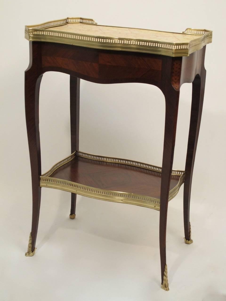 Mahogany Louis XVI side table with brass gallery around inset marble top. Having herringbone inlay detail, canted corners, and cabriole legs ending in brass sabots. French, circa 1890.