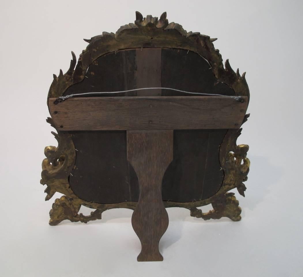 An impressive, beautifully carved and gilt 18th century Italian mirror. Original mirror shows appropriate signs of age and wear. The brace or easel on the back was probably added in the 20th century.