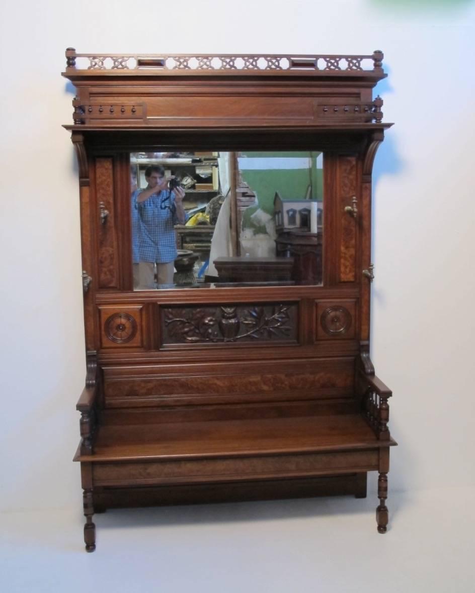 A large Victorian period hall bench and coat rack. Burled walnut raised center panels and carved center panel of an owl on a tree branch, beveled mirror, brass coat hooks.  American, Circa 1880.