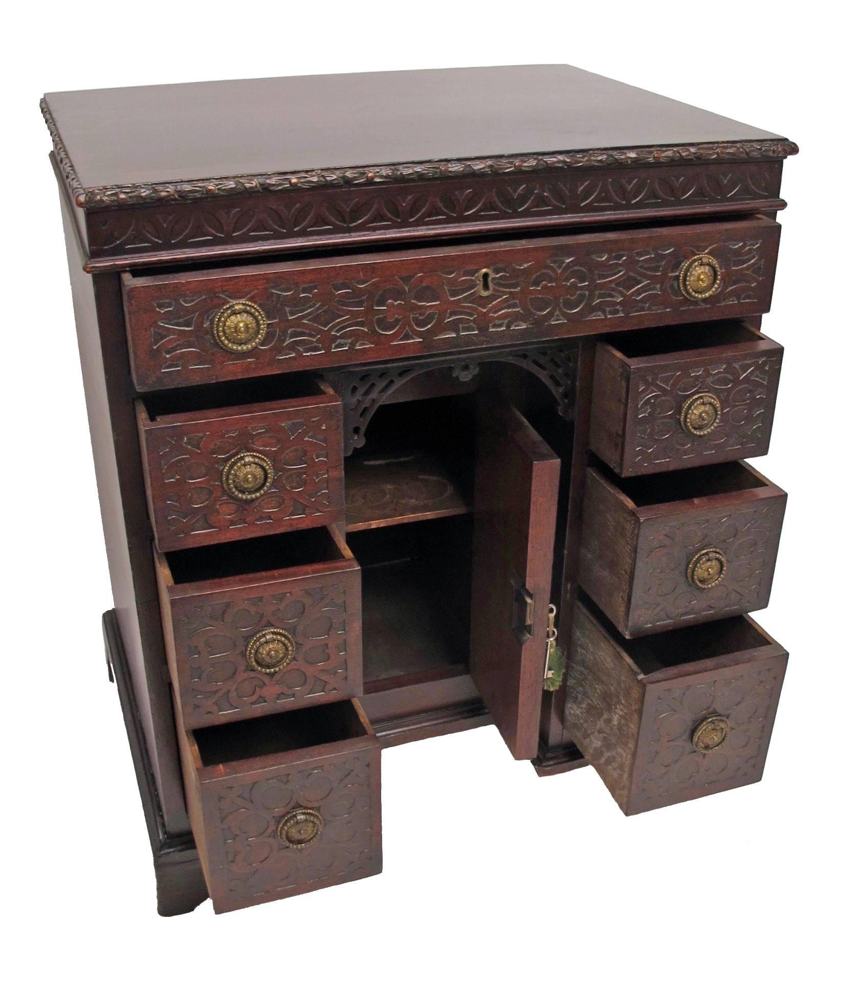 Georgian Mahogany Desk or Dressing Table.  Blind fret carving around the edge of the top and on the drawer fronts.  Single long drawer above three drawers on each side of the kneehole with cupboard all with brass ring pulls standing on bracket feet.