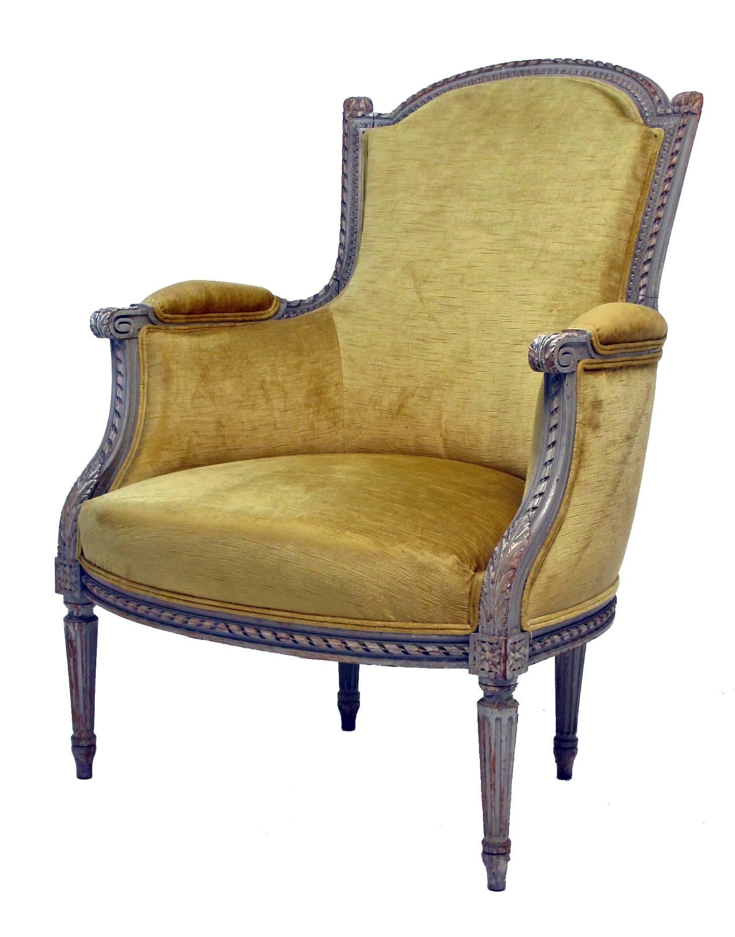 A remarkably comfortable hand-carved and hand-painted armchair or Louis XVI style bergere chair with ottoman, upholstered in slightly worn silk velvet fabric. Ottoman measures 16