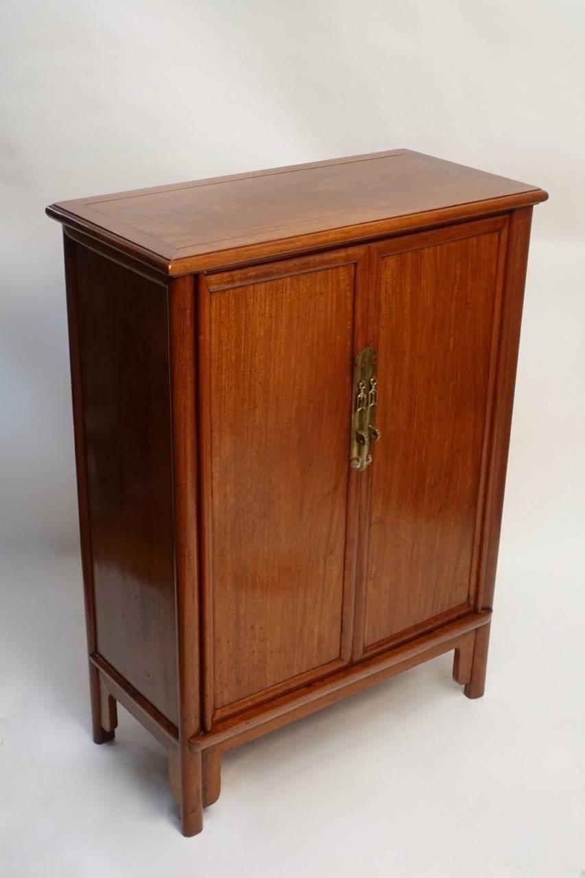 A matched pair of teak wood two-door cabinets with brass hardware and interior shelf, China, circa 1960s.