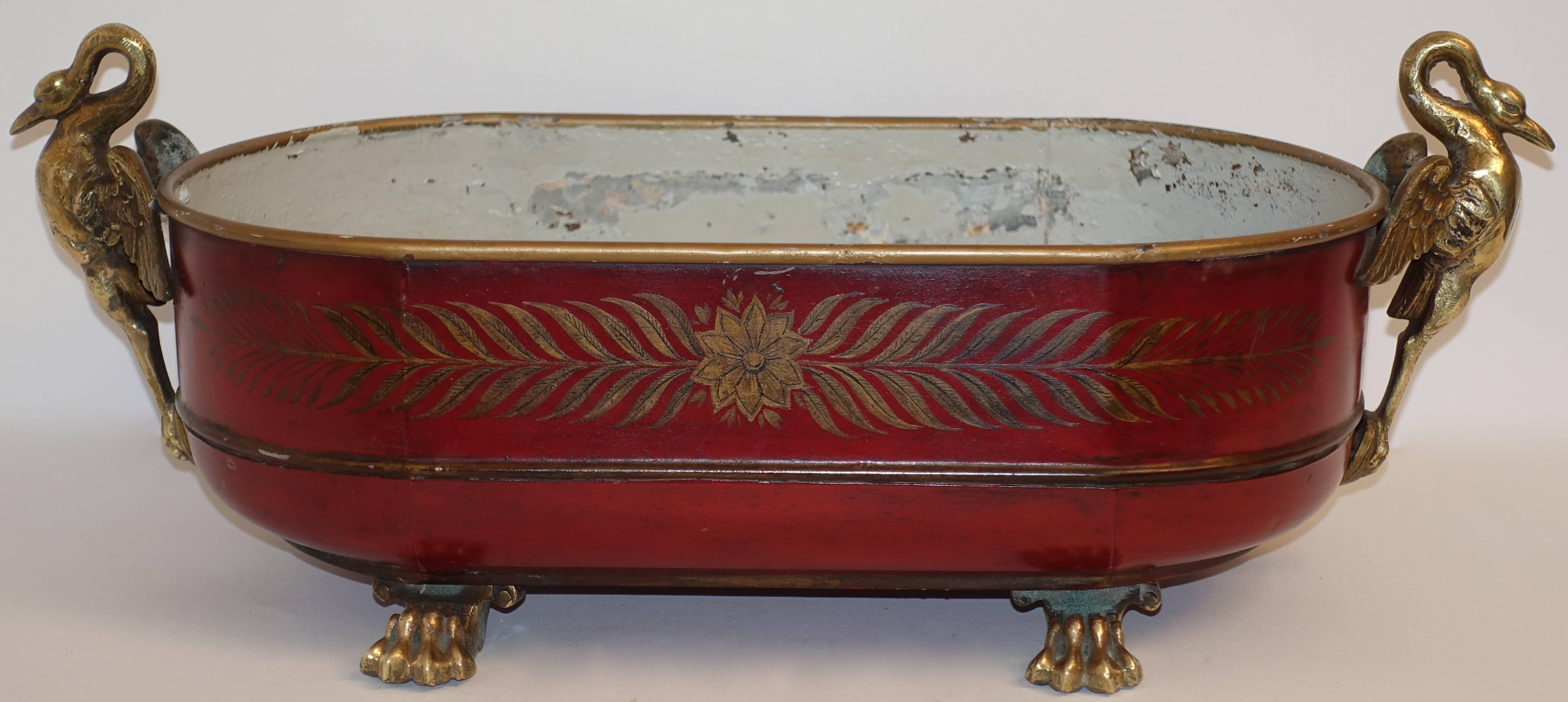 Empire style oval red painted tole cachpot with brass swans and lion paw feet. Gilt arrow decoration on both sides, French, late 19th century.