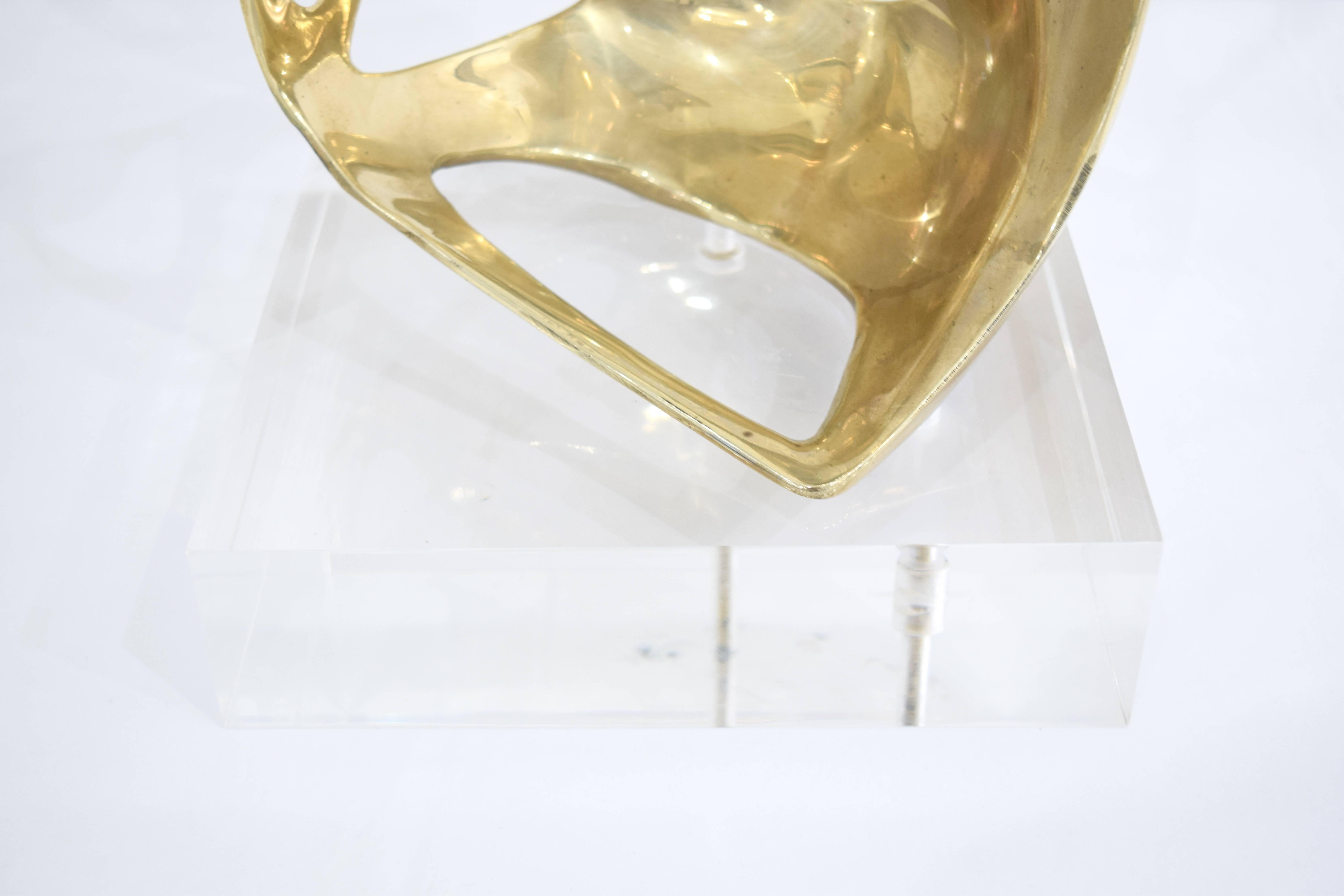 A Mid-Century Modern Lucite and brass abstract sculpture in the form of a human like depiction.