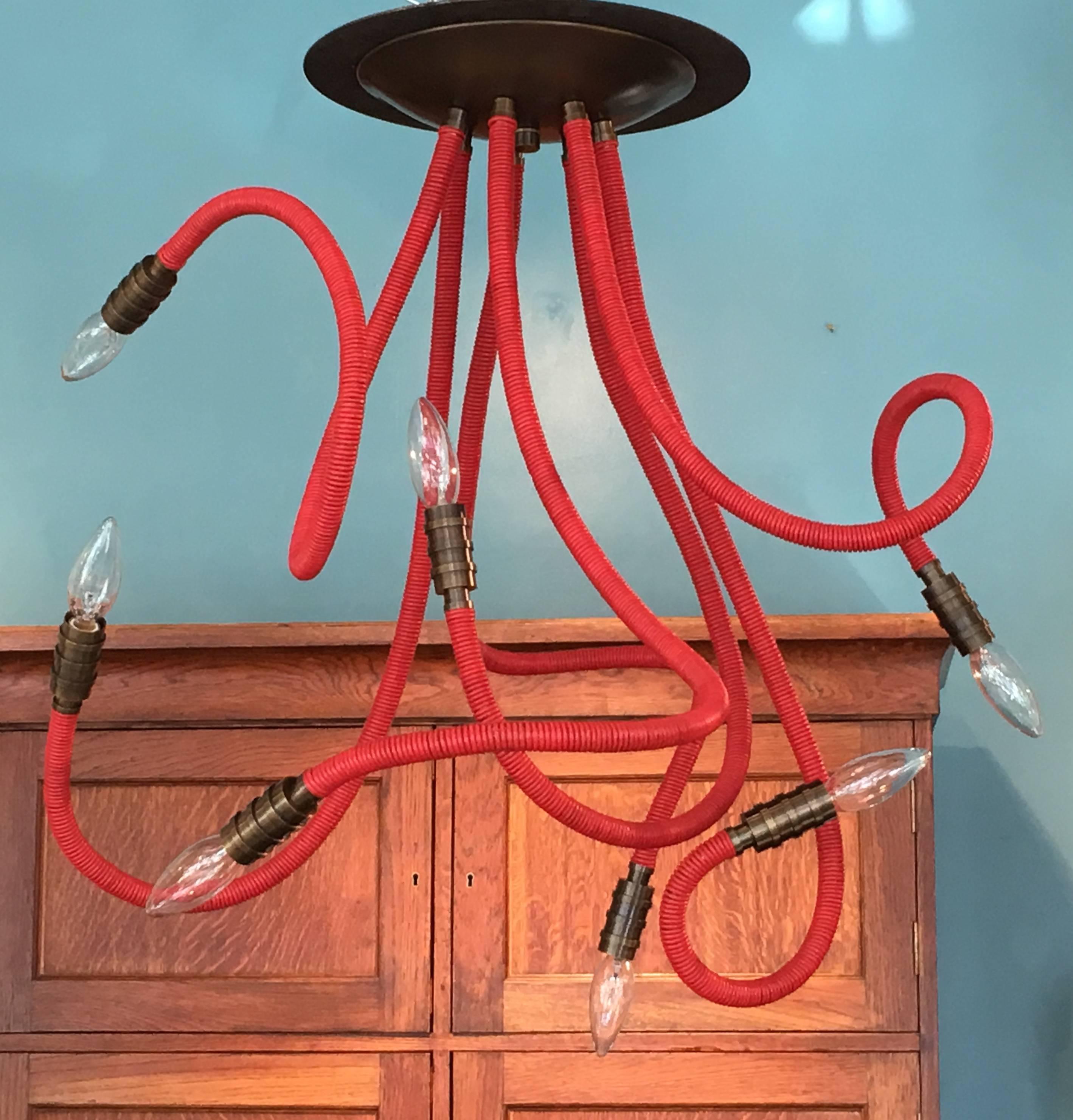 Seven-arm Meander ceiling mount chandelier with antique brass fittings, shown in custom red leather. Adjustable arms are 38
