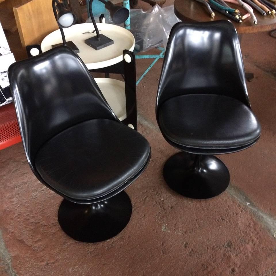 Pair of Eero Saarinen tulip chairs with black swivel frame and black leather seat cushion, knoll sticker, circa 1984.