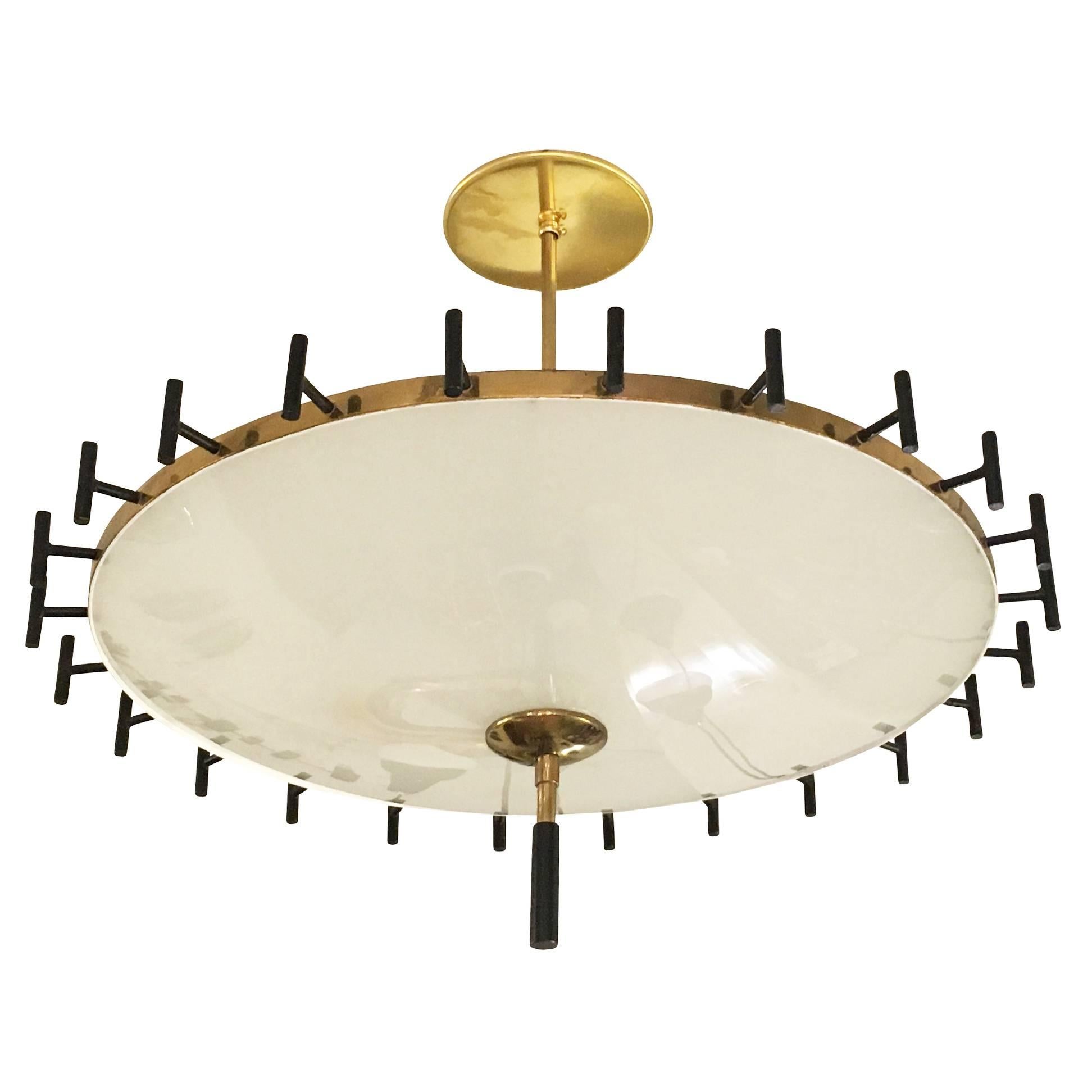 Italian midcentury chandelier with black and brass details. It has a glass shade on the bottom and top. Holds four candelabra sockets and can be mounted on a stem of any length.

Measures: Diameter 22"

Height 20".
   
Available for