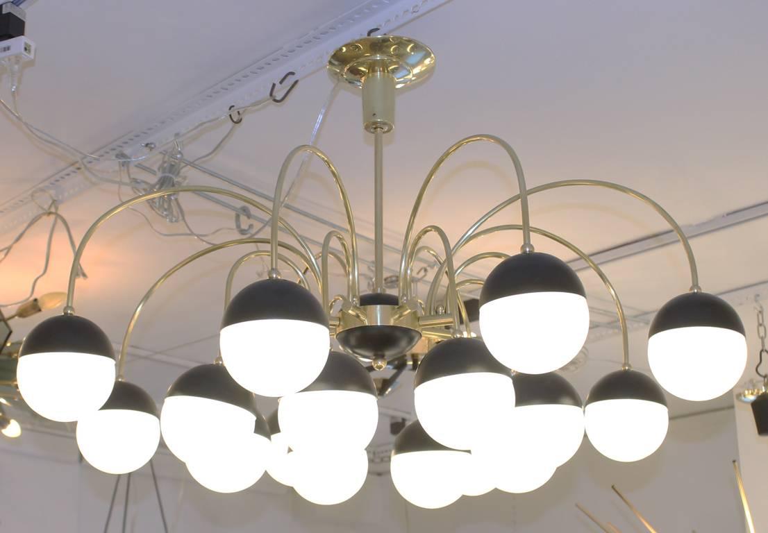 Large and elegant Stilnovo attributed chandelier with eight brass arms. Each arm hold two sphere shaped shades with candelabra sockets. The shades are white frosted glass and clip on to black painted metal cups. Frame can be flipped to have the