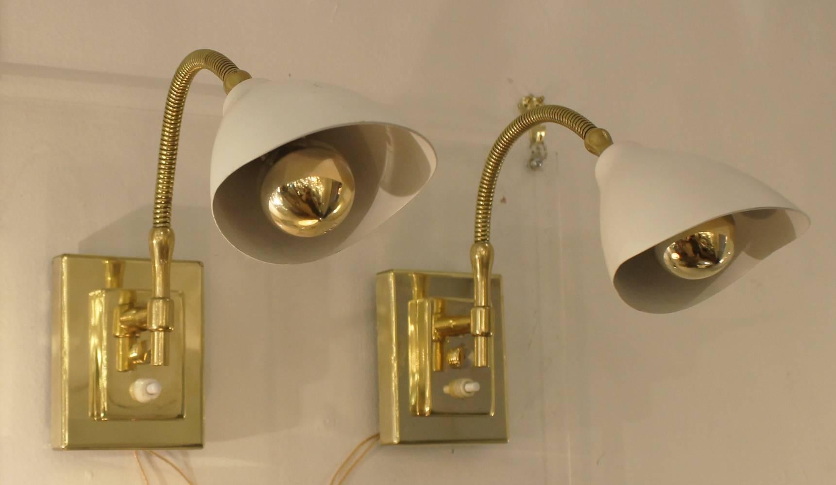 Adjustable arm sconces attributed to Gino Sarfatti. All brass except for the shades which are white painted aluminum. Each hold one candelabra socket and has a push switch on the back plate.
