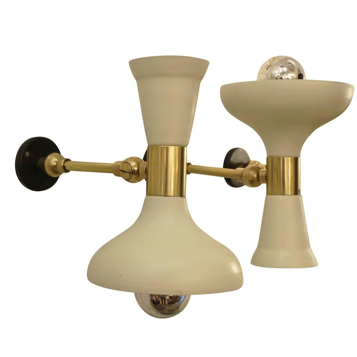Elegant pair of sconces with white shades. The inside of the shades is painted white while the adjustable arms are brass. Each holds one candelabra socket. A second pair with dark green shades is also available and the color can be changed upon