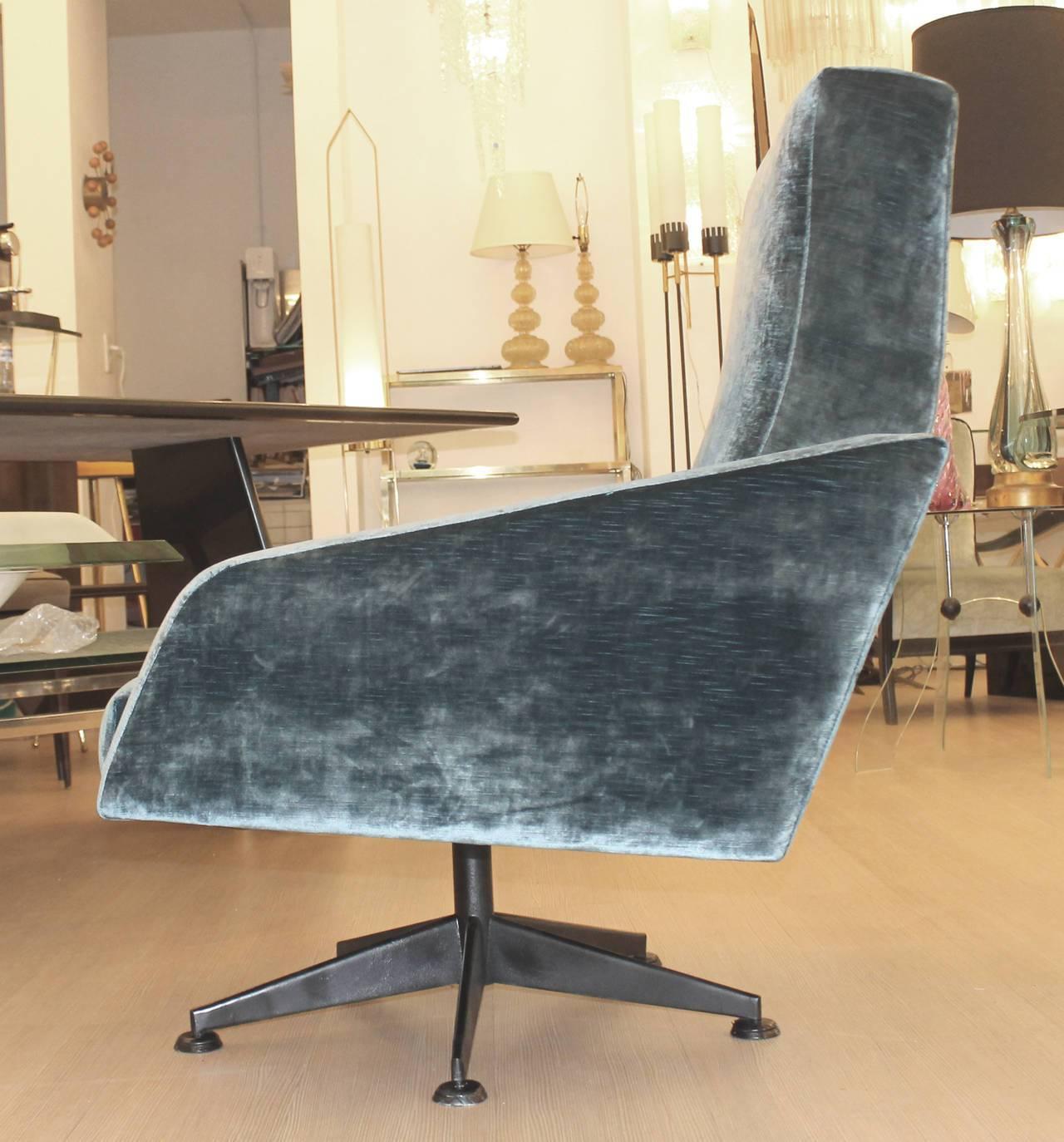 Elegant pair of swivel lounge chairs characterized by straight and diagonal lines. Very comfortable, the seat is on a black swivel base that turn 360 degrees. This is a great example of Mid-Century Italian design. One armchair has been