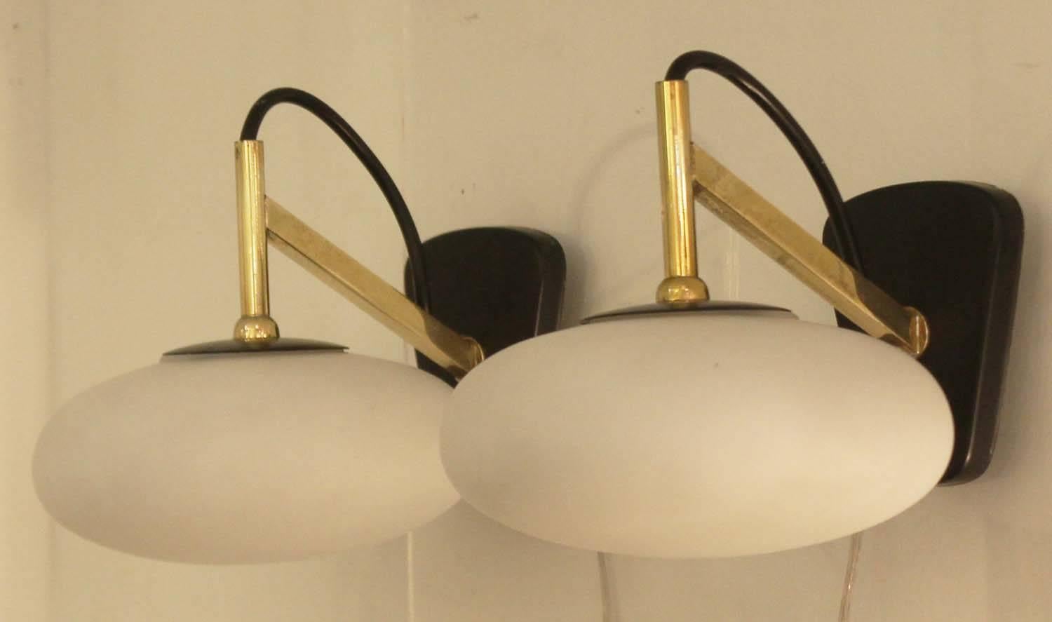 Small and charming sconce in the manner of Arredoluce. Features an oval frosted glass shade, brass stem and black back plate. Larger back plate to cover US electrical box included.
