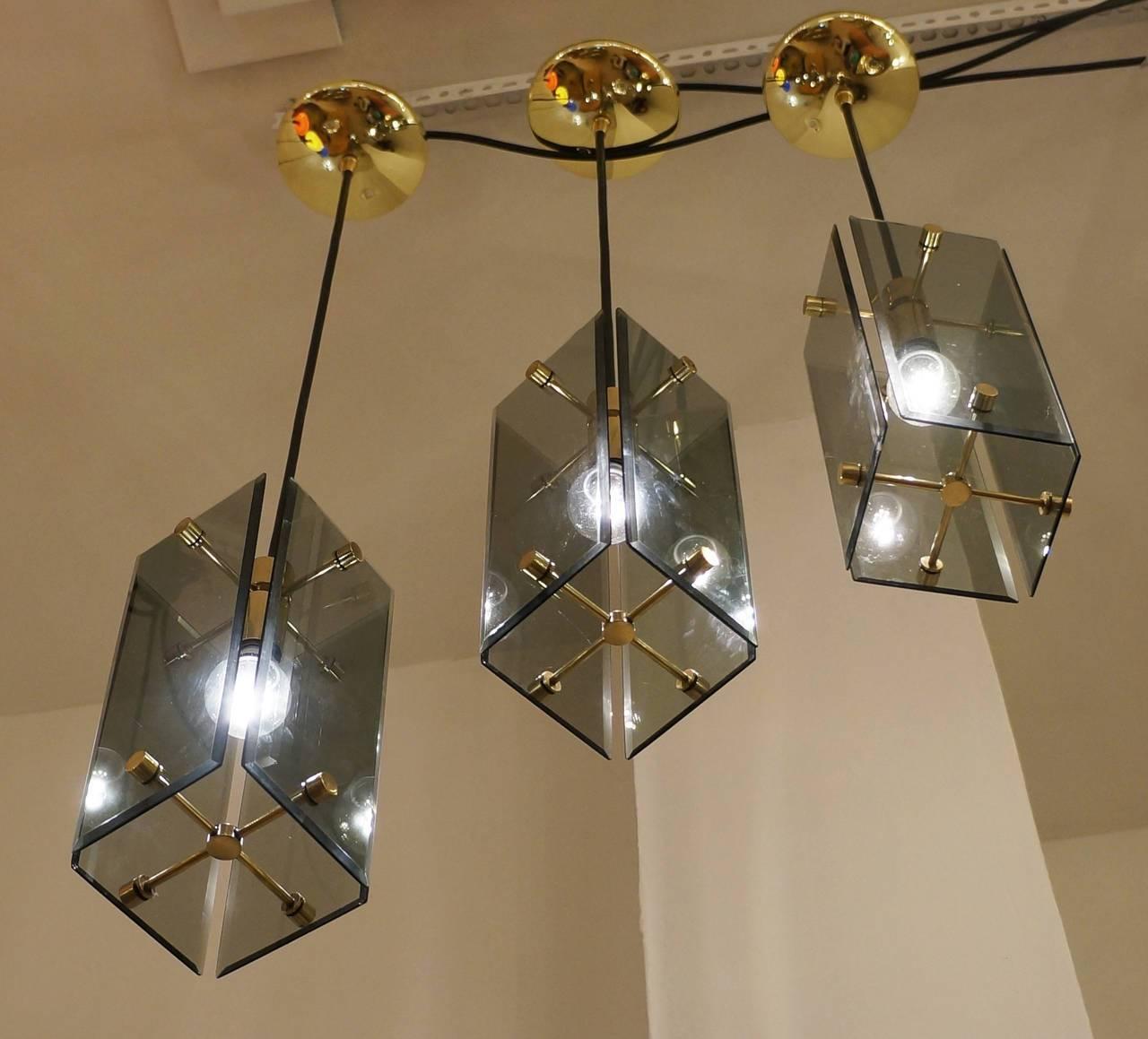 Gracious set of Italian 1960s pendants with brass structure and dark green glasses. The edges of the glasses are beveled. Re-wired with candelabra sockets. Height can be easily adjusted by extending or shorting the wire.
