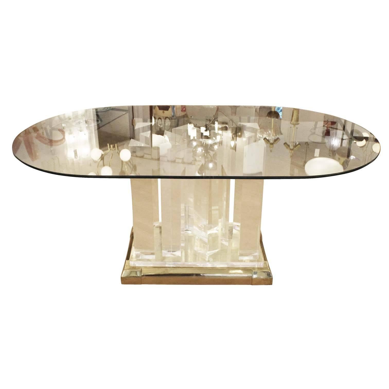 Breathtaking dining table in the style of American architect Jeffrey Bigelow featuring a brass-plated pedestal, Lucite base and oval glass top. The Lucite base is composed of triangular 