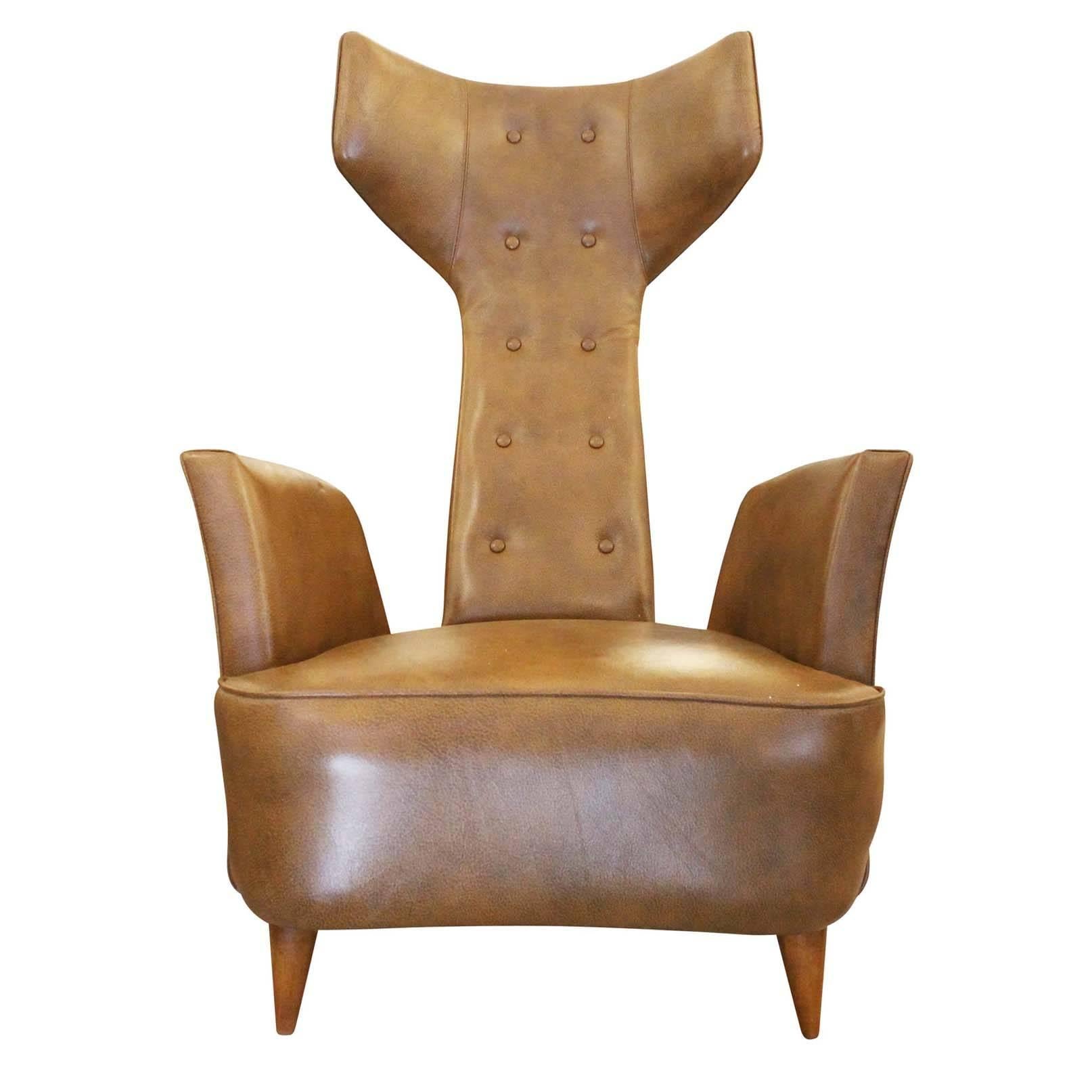 Sculptural leather armchair featuring a high back with wings and wood feet. Modern limited edition production Inspired by Mid-Century design. Second one available upon request.