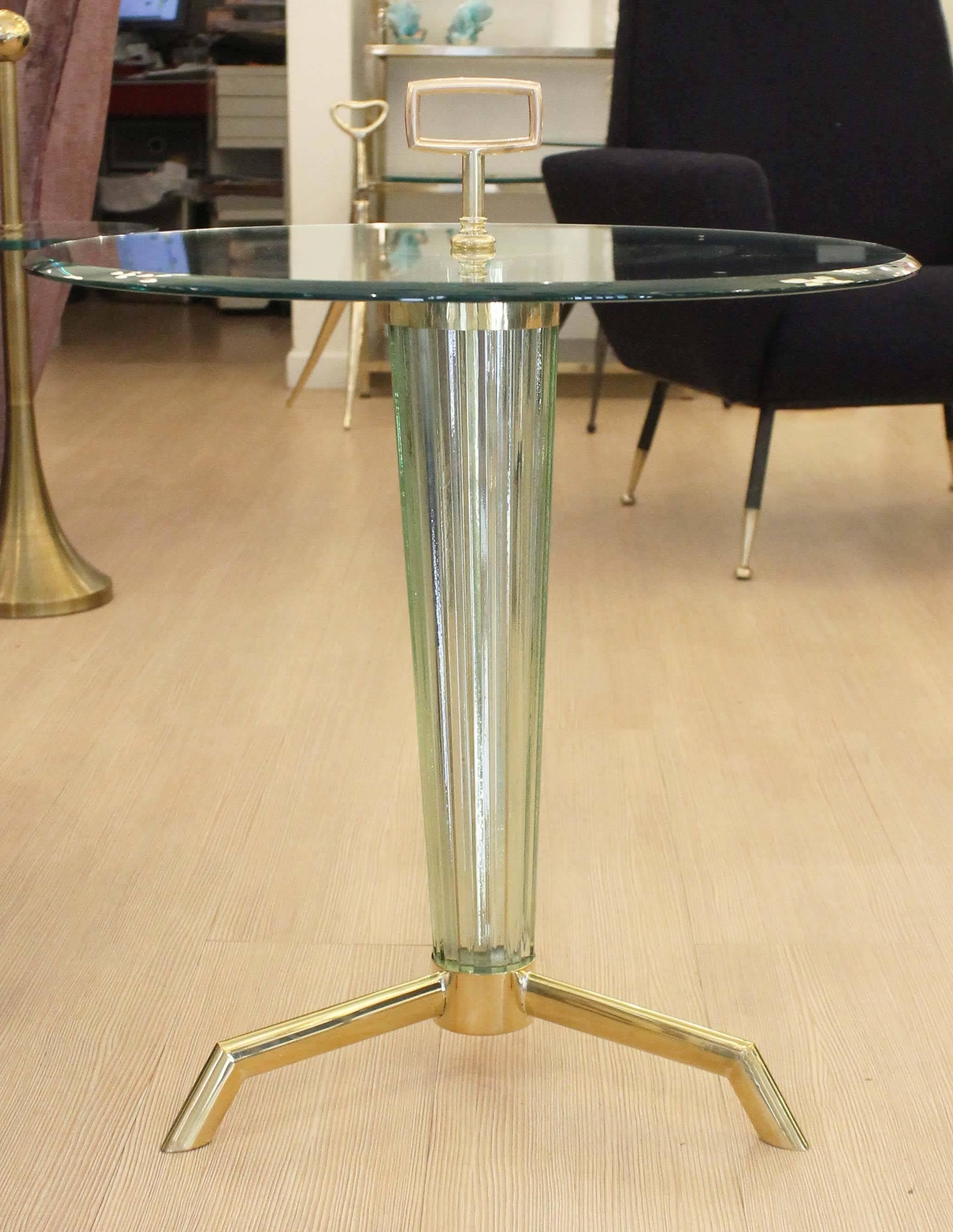 Elegant gueridon or side table with brass feet and handle. The body is a light acqua color ribbed glass. The clear glass top is beveled.