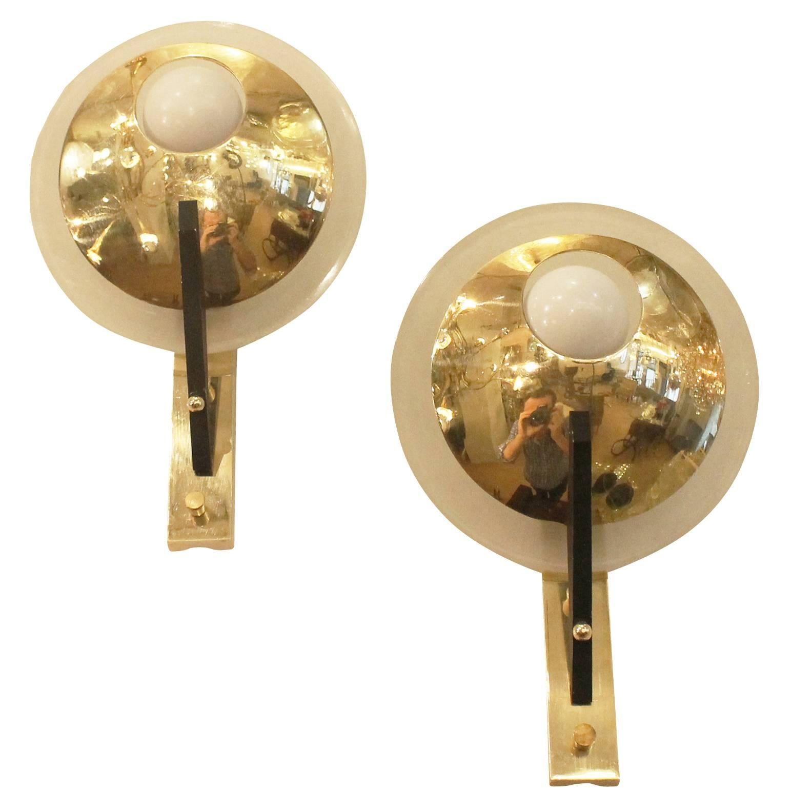 Charming diminutive wall lights by Stilnovo made of brass, glass and black painted metal. The single candelabra light bulb is partially covered at the front by a brass plate and at the back by a frosted glass plate. Perfect for adding a touch of
