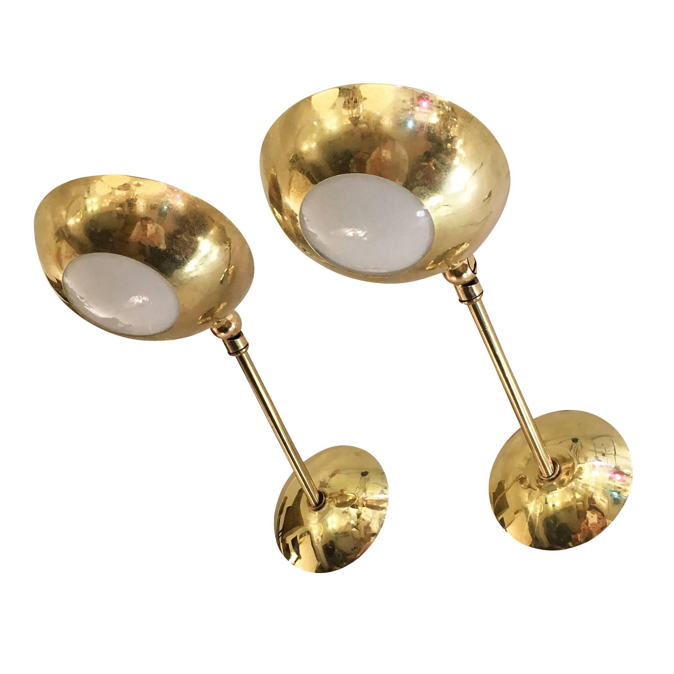 Elegant pair of brass sconces in the manner of Stilnovo. The shades have a frosted glass center and are adjustable 180 degrees. Each holds one candelabra socket.

Measures: Width: 4.5".

Depth: Approximate 7"-10" depending on shade