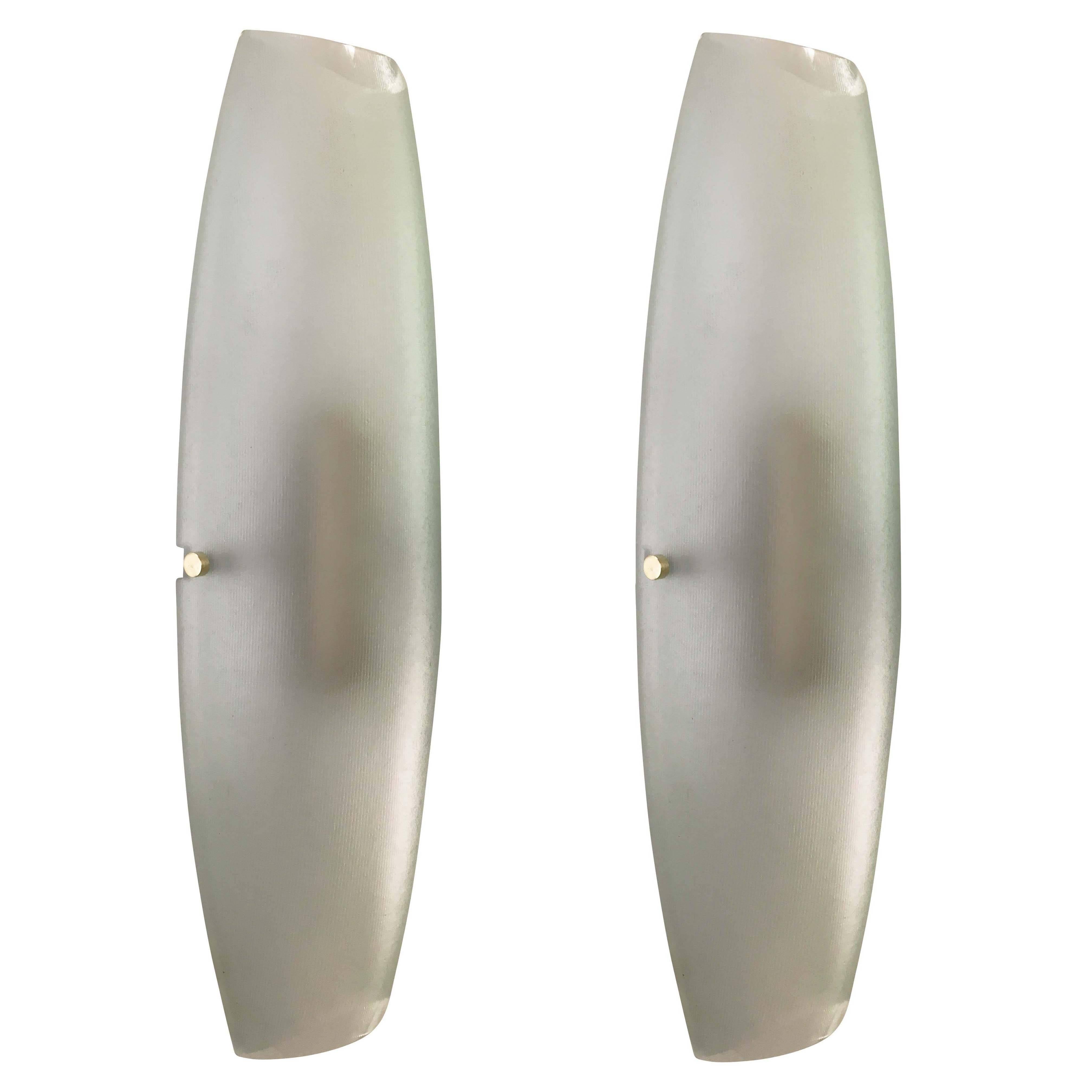 Fontana Arte wall lights model 2027 designed by Max Ingrand in the 1960s. Each features a light green ribbed glass on a white lacquered frame holding two candelabra sockets. To note are the exquisite details such as the brass fittings and glass ends