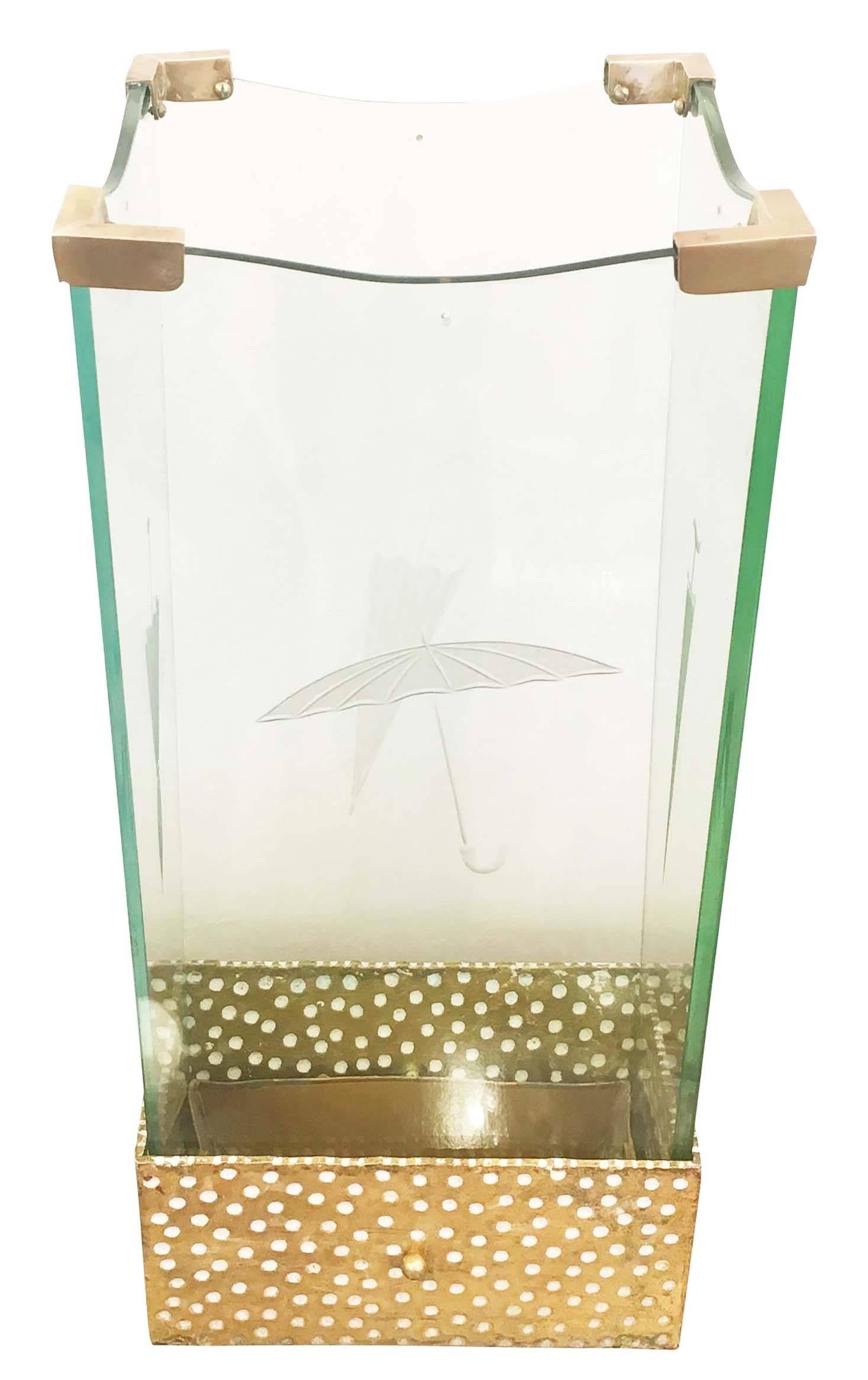 Playful glass and brass umbrella stand by crystal Art. Each of the four glass pieces has an etched image of an umbrella. The base is lacquered gold with white dots while the hinges at the corners are brass.