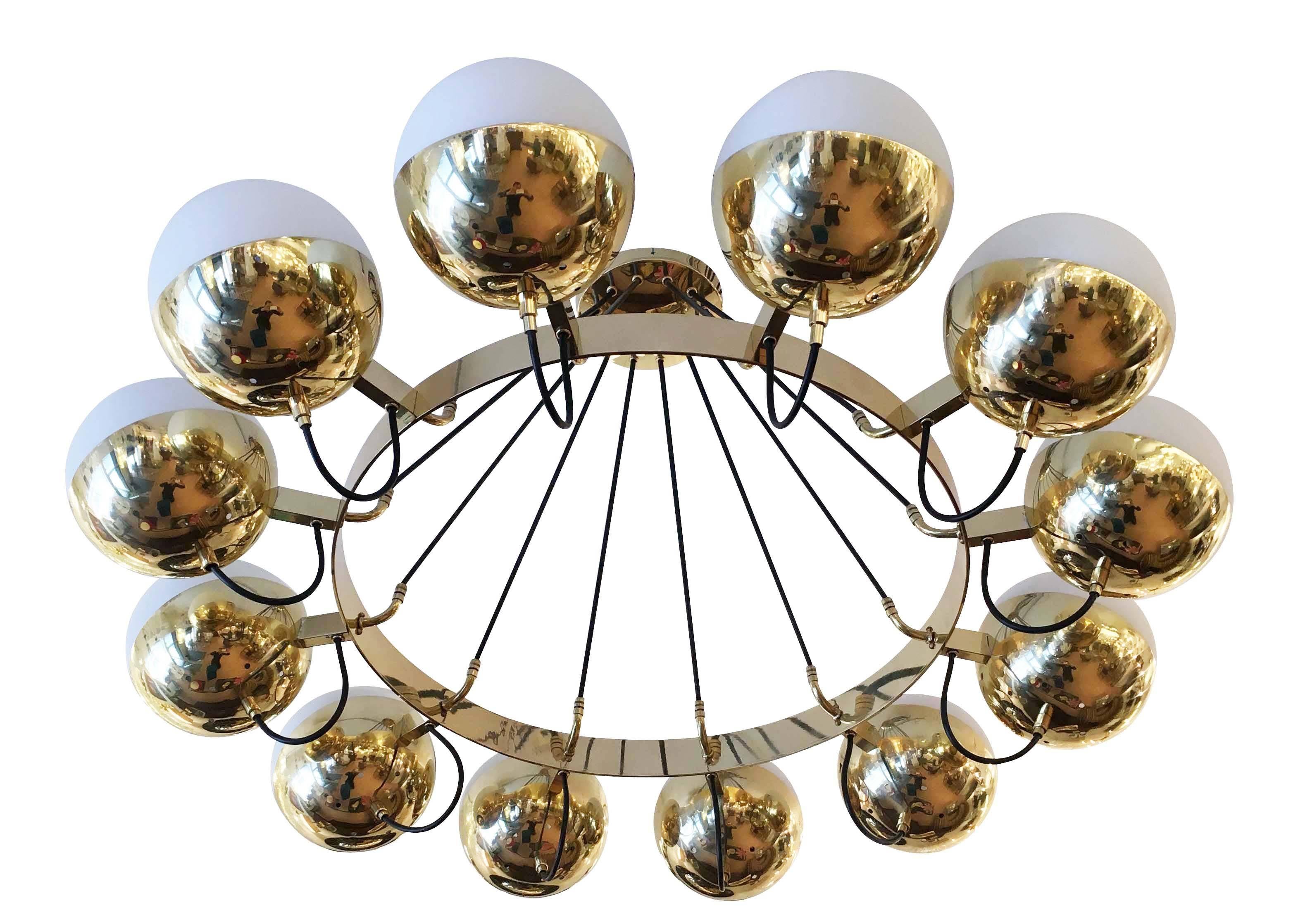 Large chandelier with a brass frame supporting twelve frosted glass shades. The electrical cords hold the main frame and connect to the flush mount canopy. Height can be adjusted as needed. 